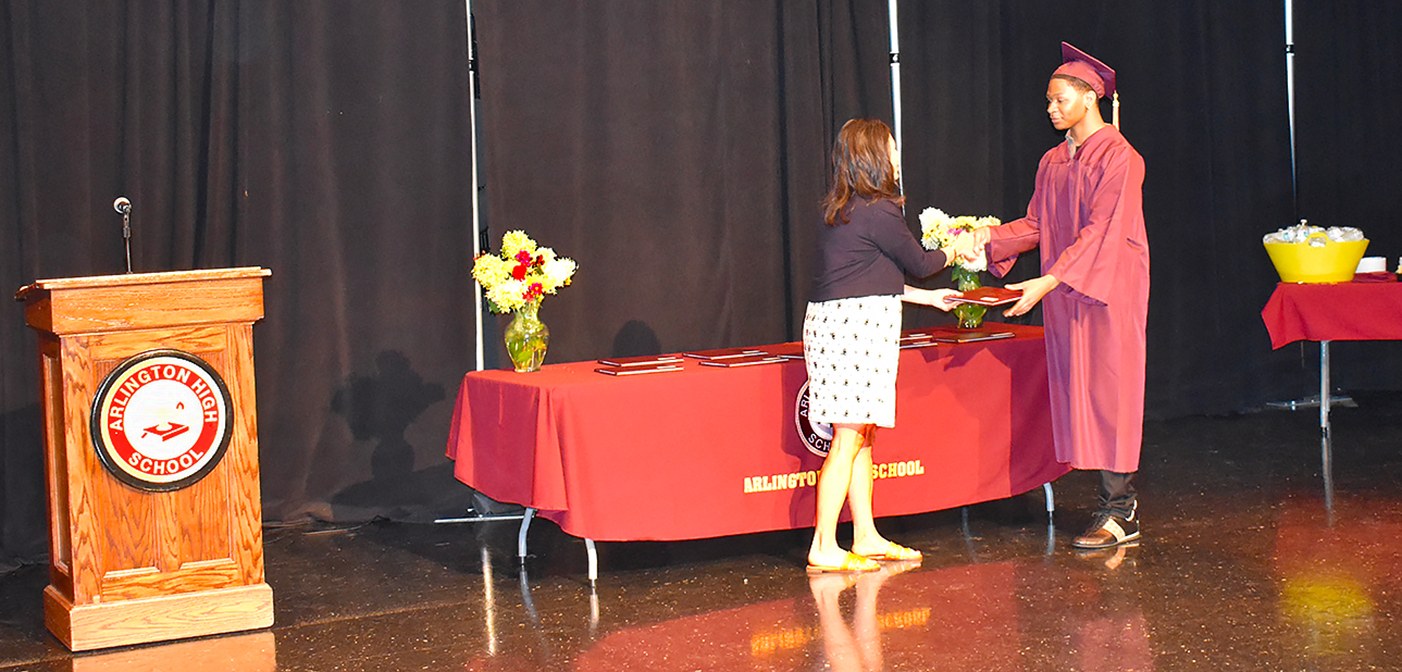 Young man in cap and gown receiving diploma
