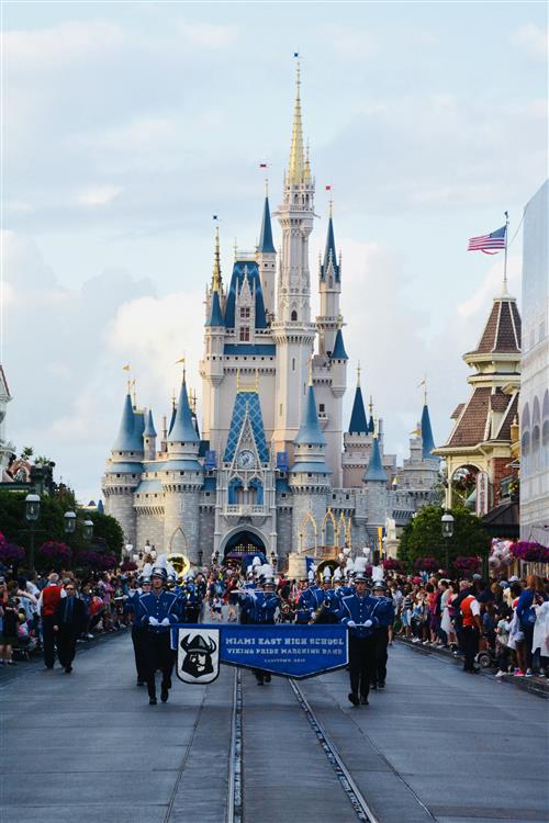 Castle at Disney World with the miami east band posing in front of it.