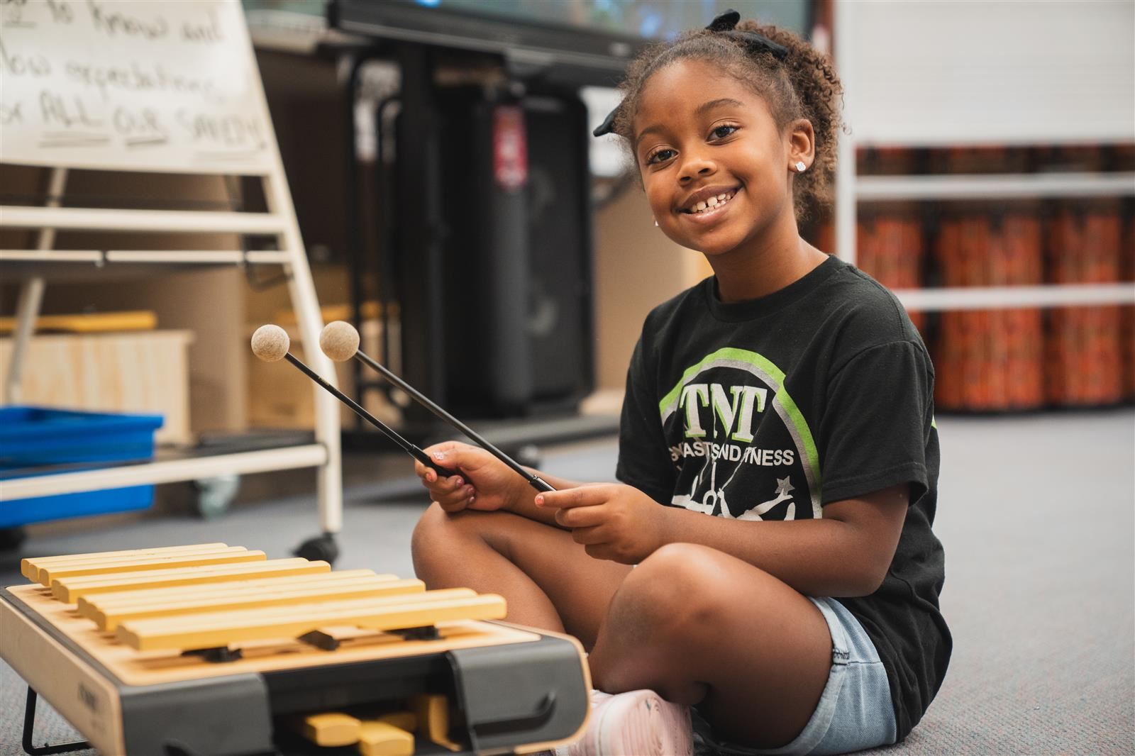 Elementary-aged girl playing an instrument and smiling