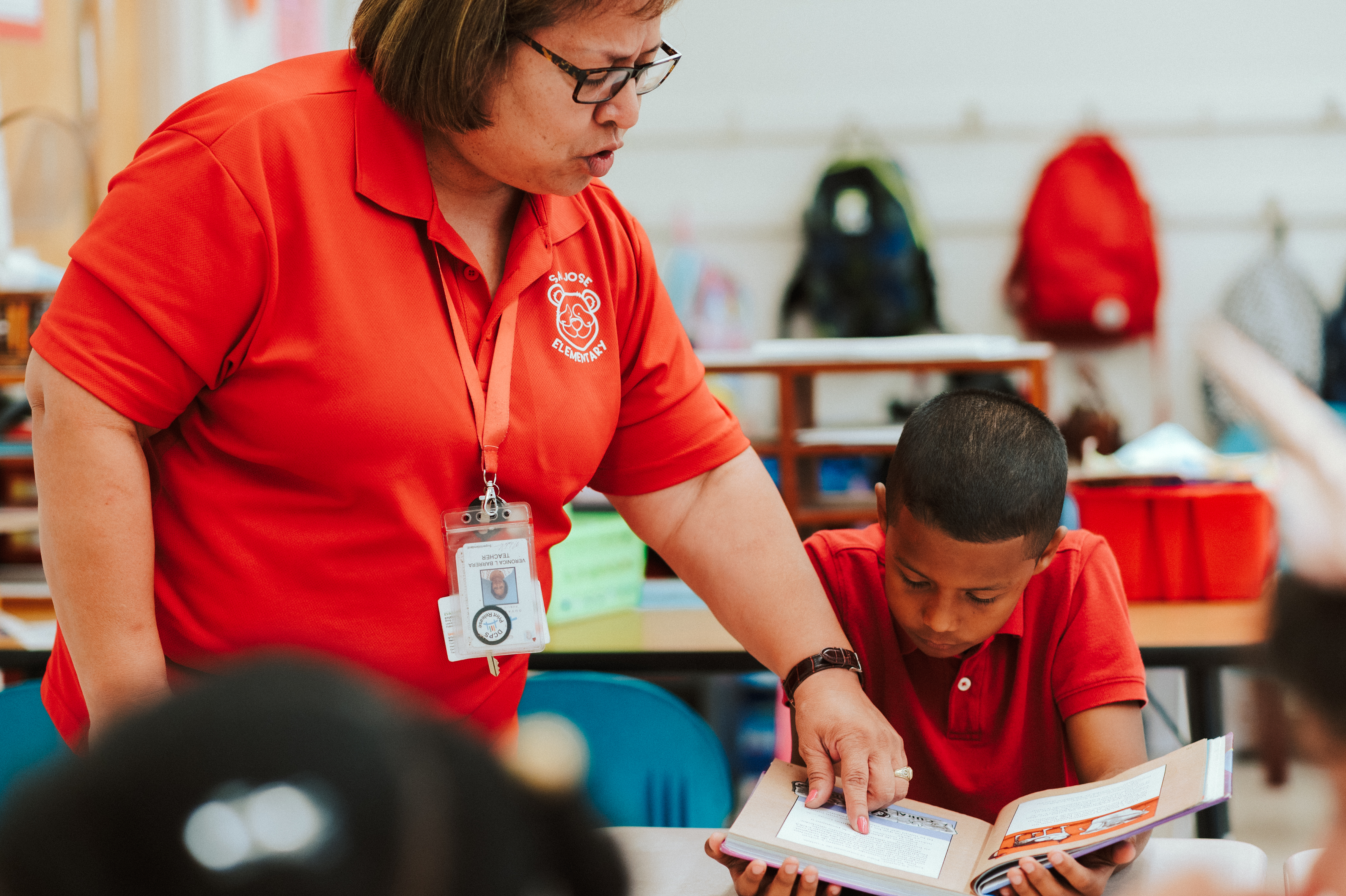 Teacher showing something to a student in a book