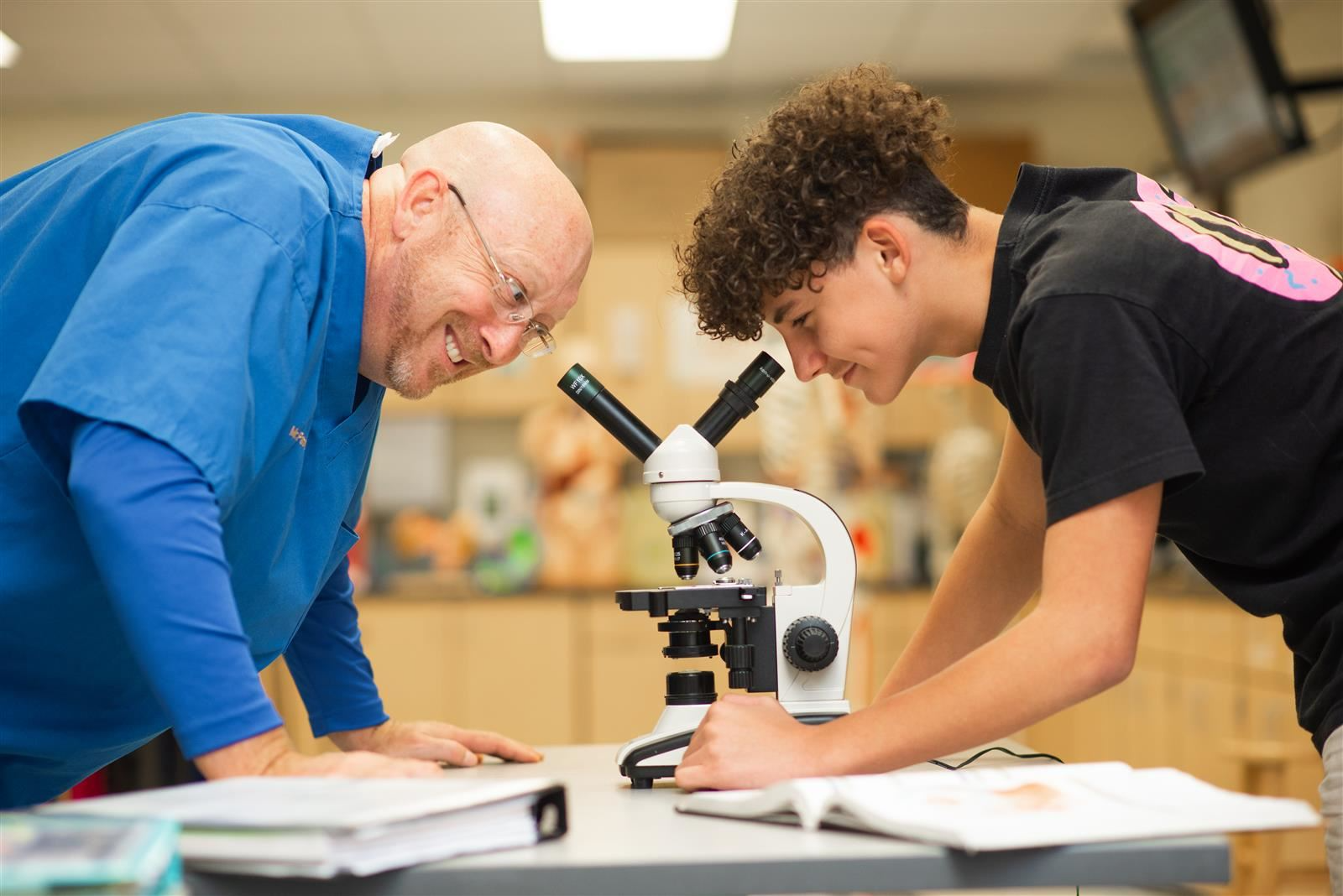 Teacher and students looking through microscope