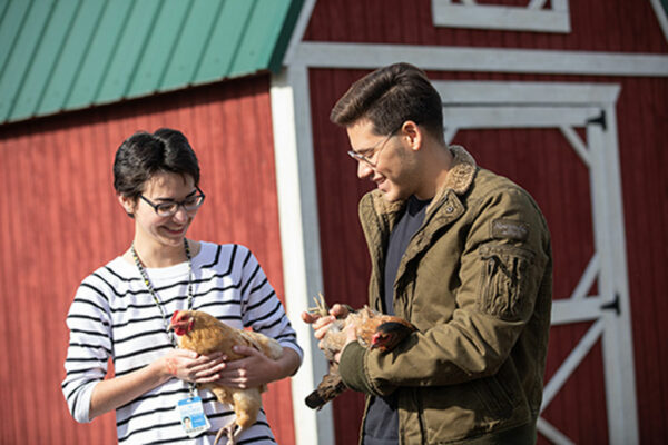 Two students holding chickens