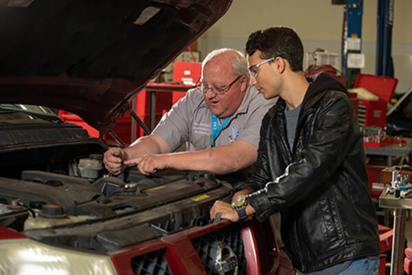 Student and teacher checking car motor