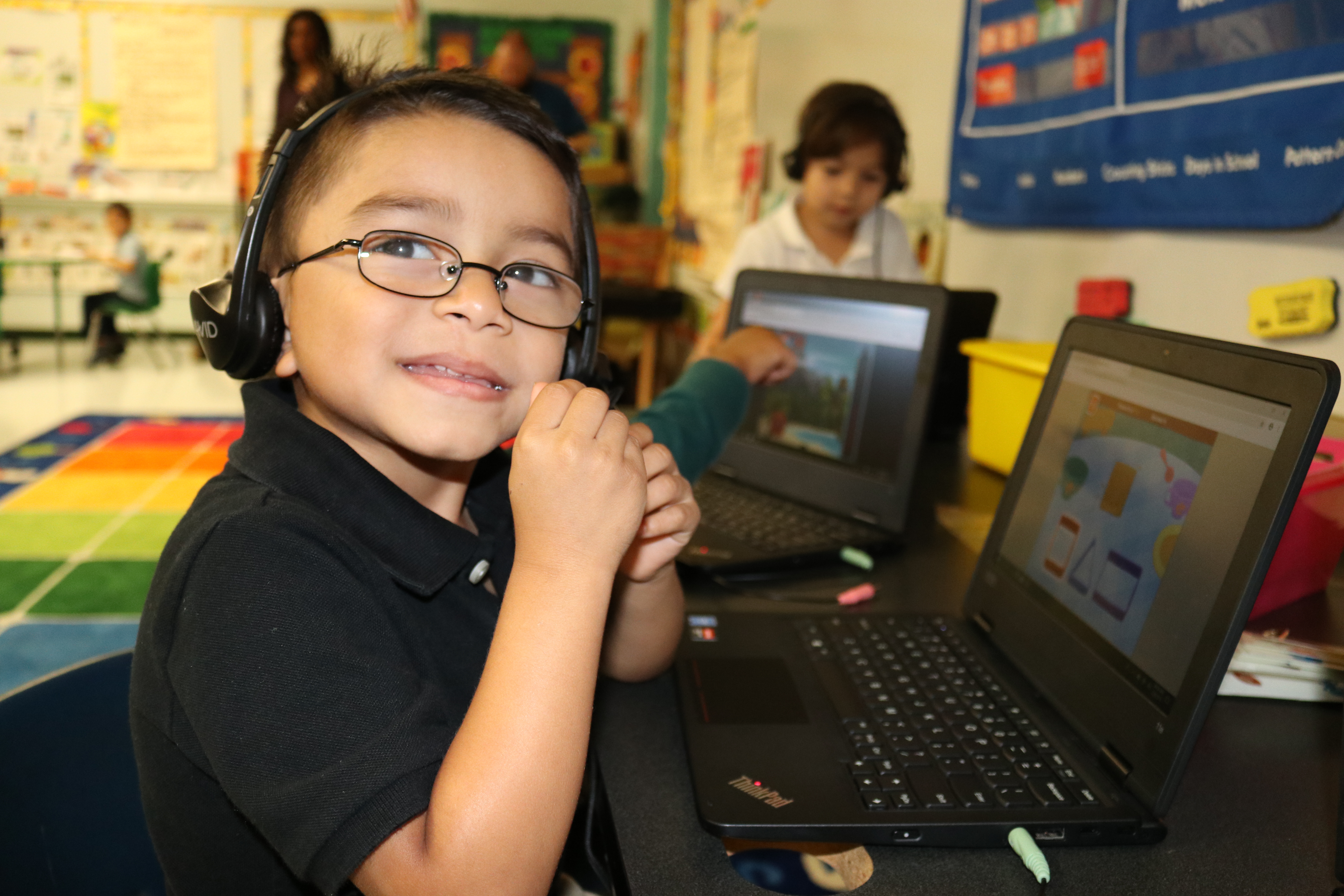 Prekindergarten student wearing headphones while on a laptop