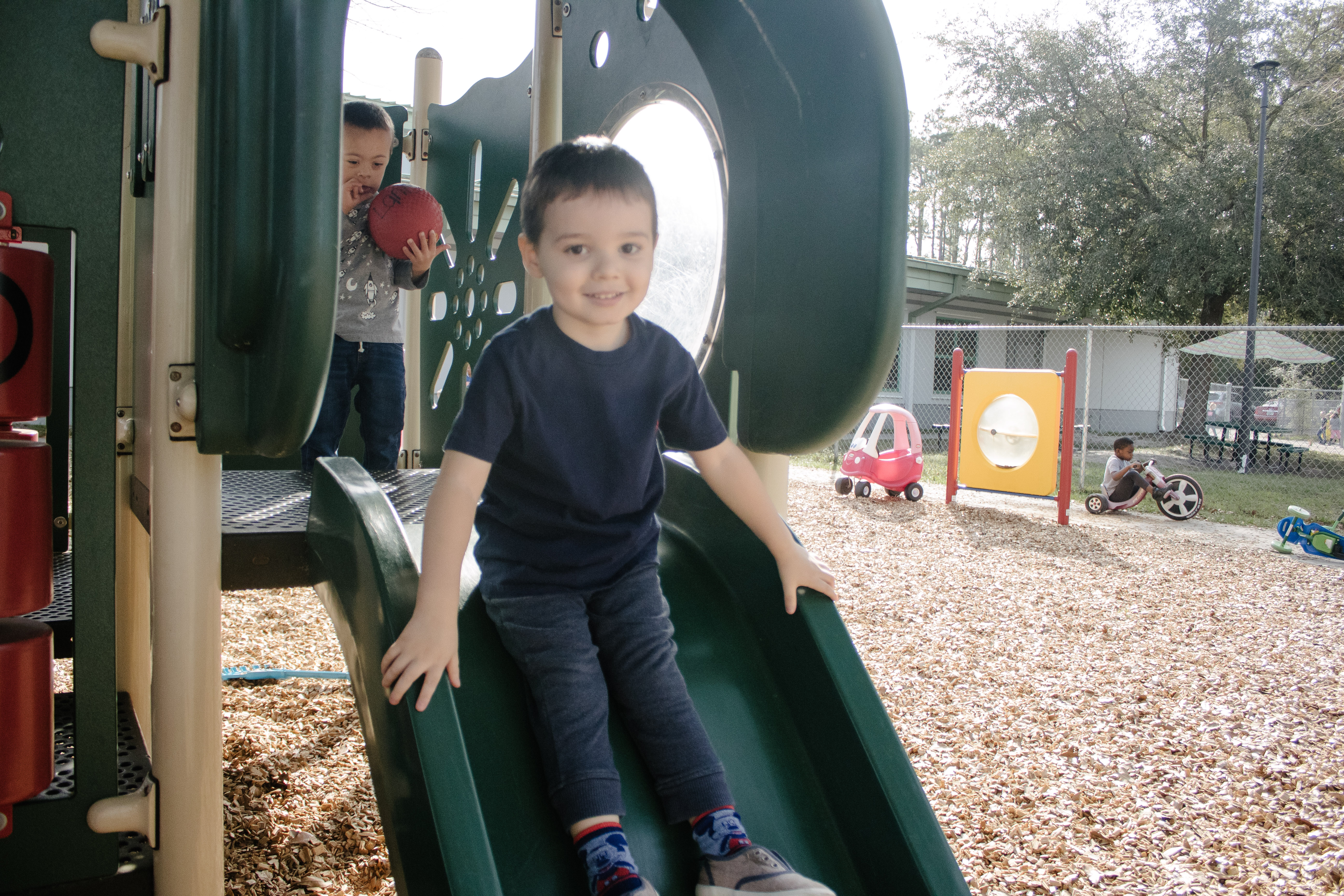 prekindergarten student going down a slide in the playground of a Duval County school