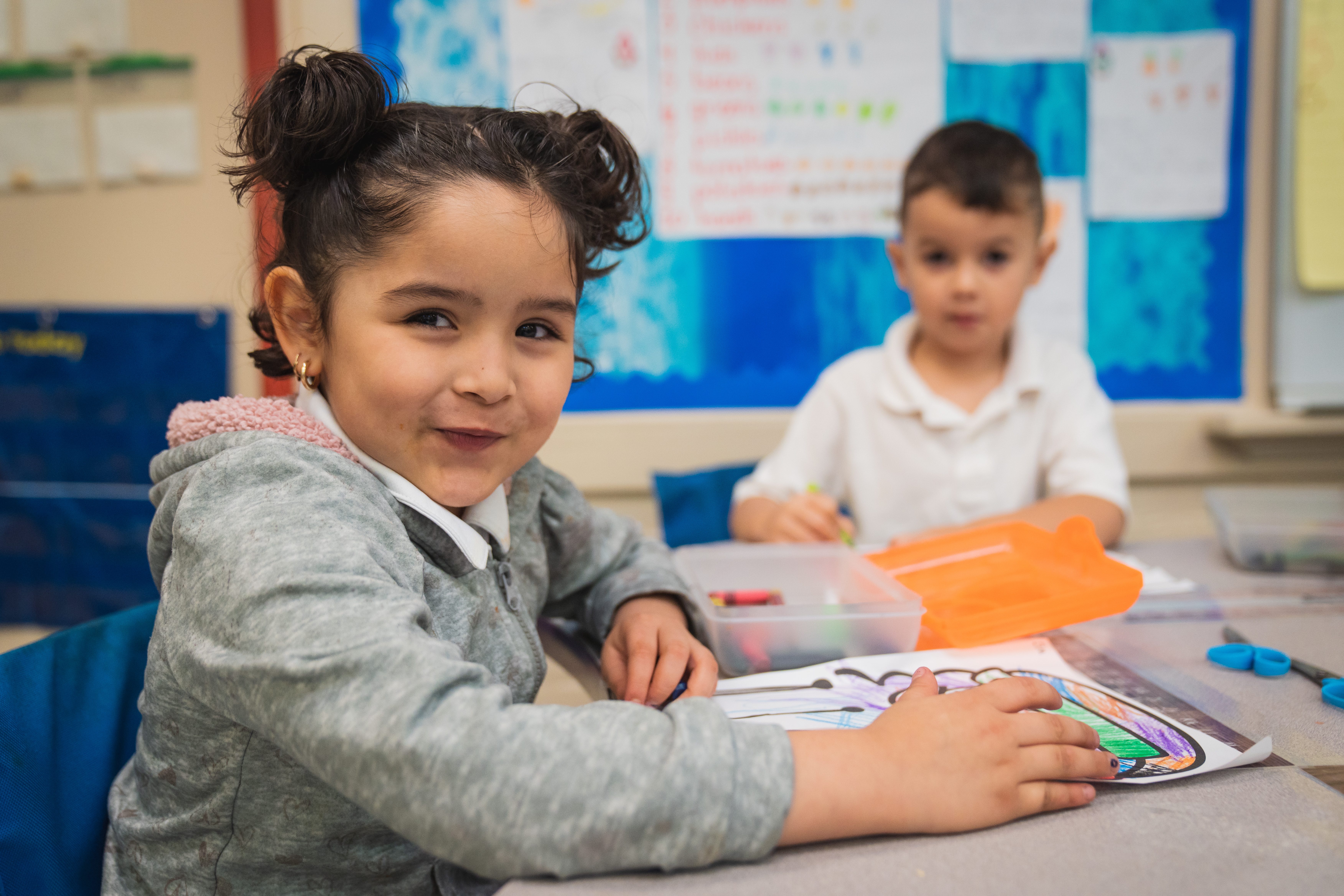 Two VPK students in classroom coloring pages at desk