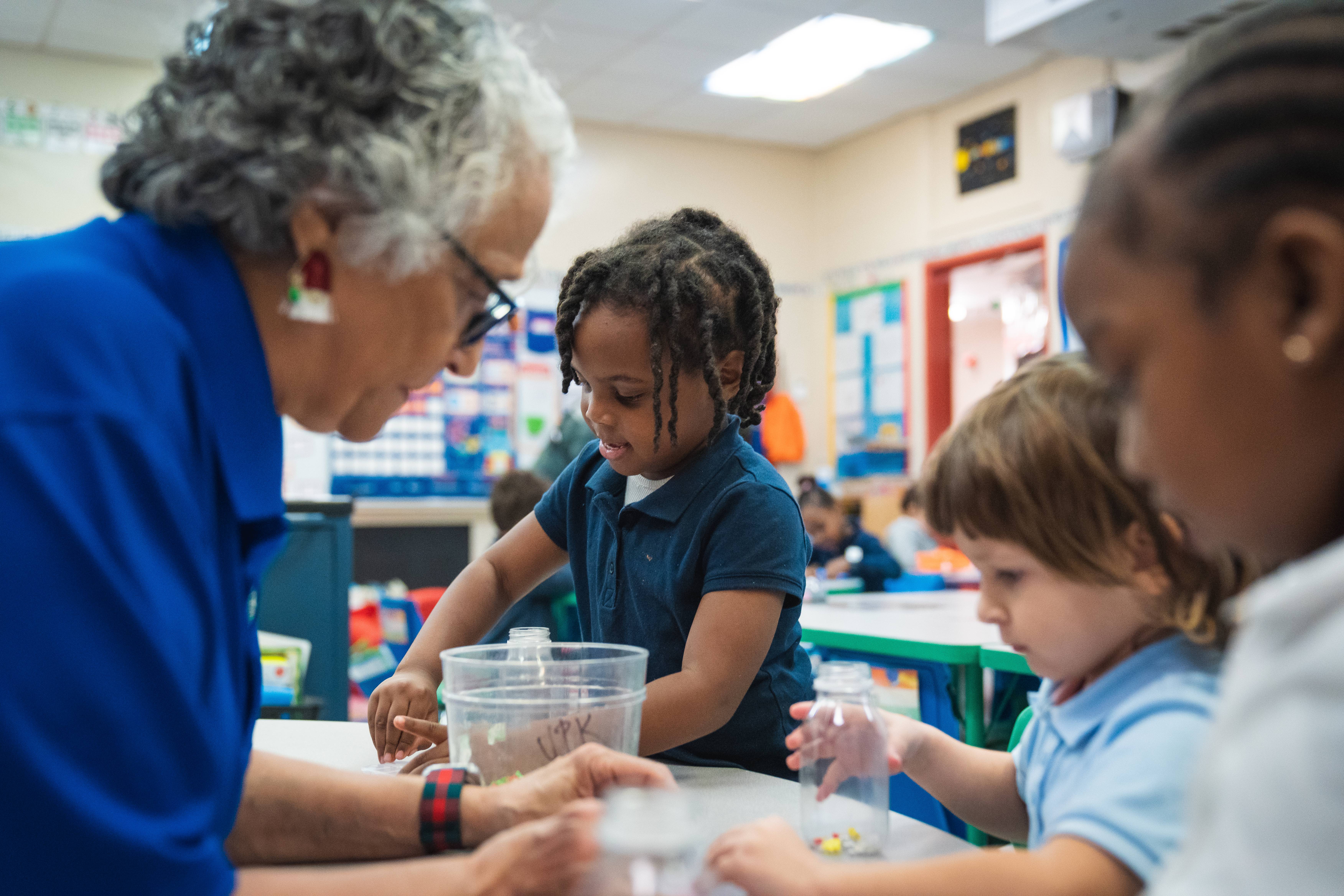 A teacher helps students with a craft in a Voluntary Prekindergarten classroom 