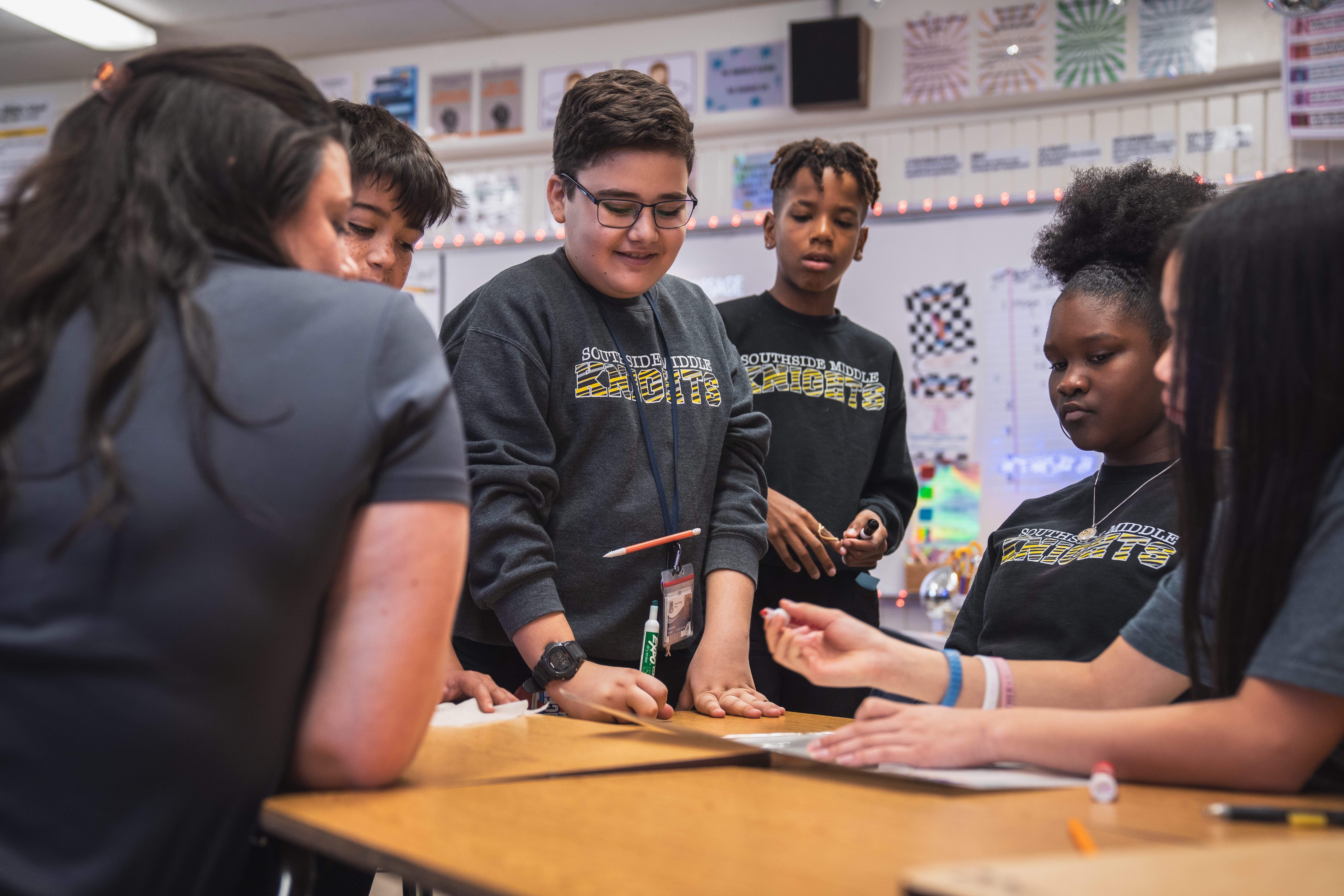 Southside Middle school students working with their teacher at a set of desks