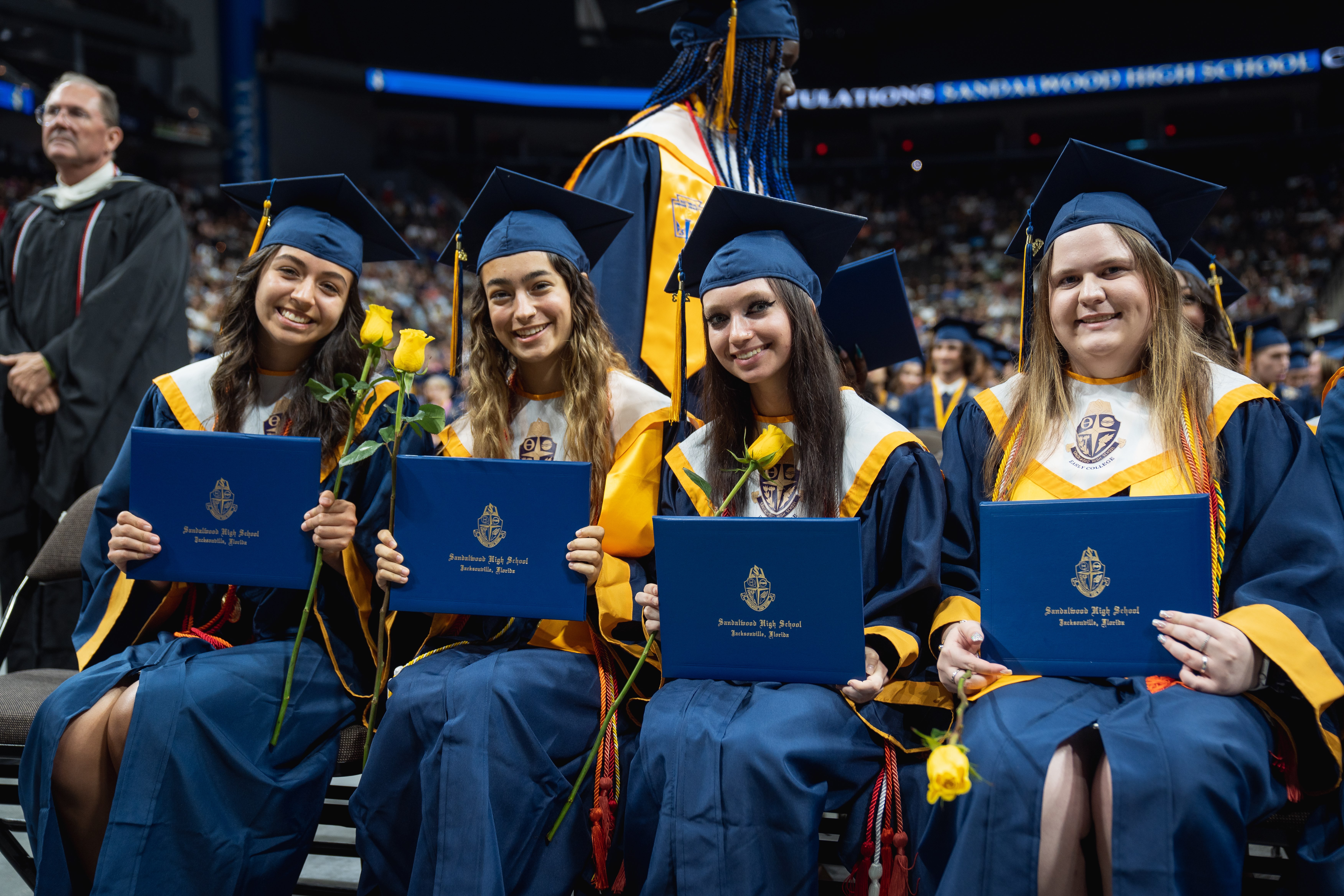 Four Sandalwood High School graduates celebrate academics in Duval County holding their diplomas