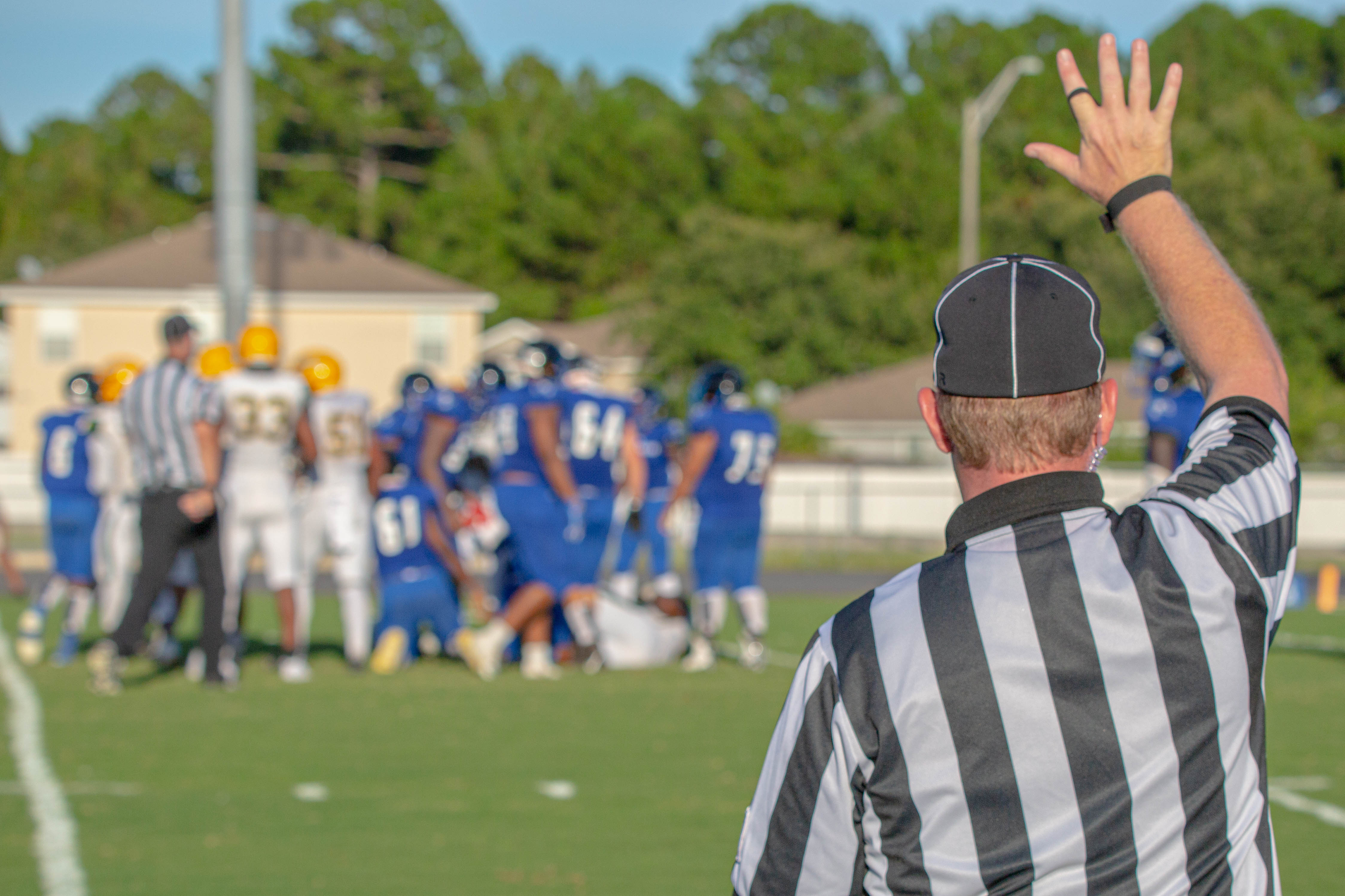 Football game with a referee in the foreground holding up his hand