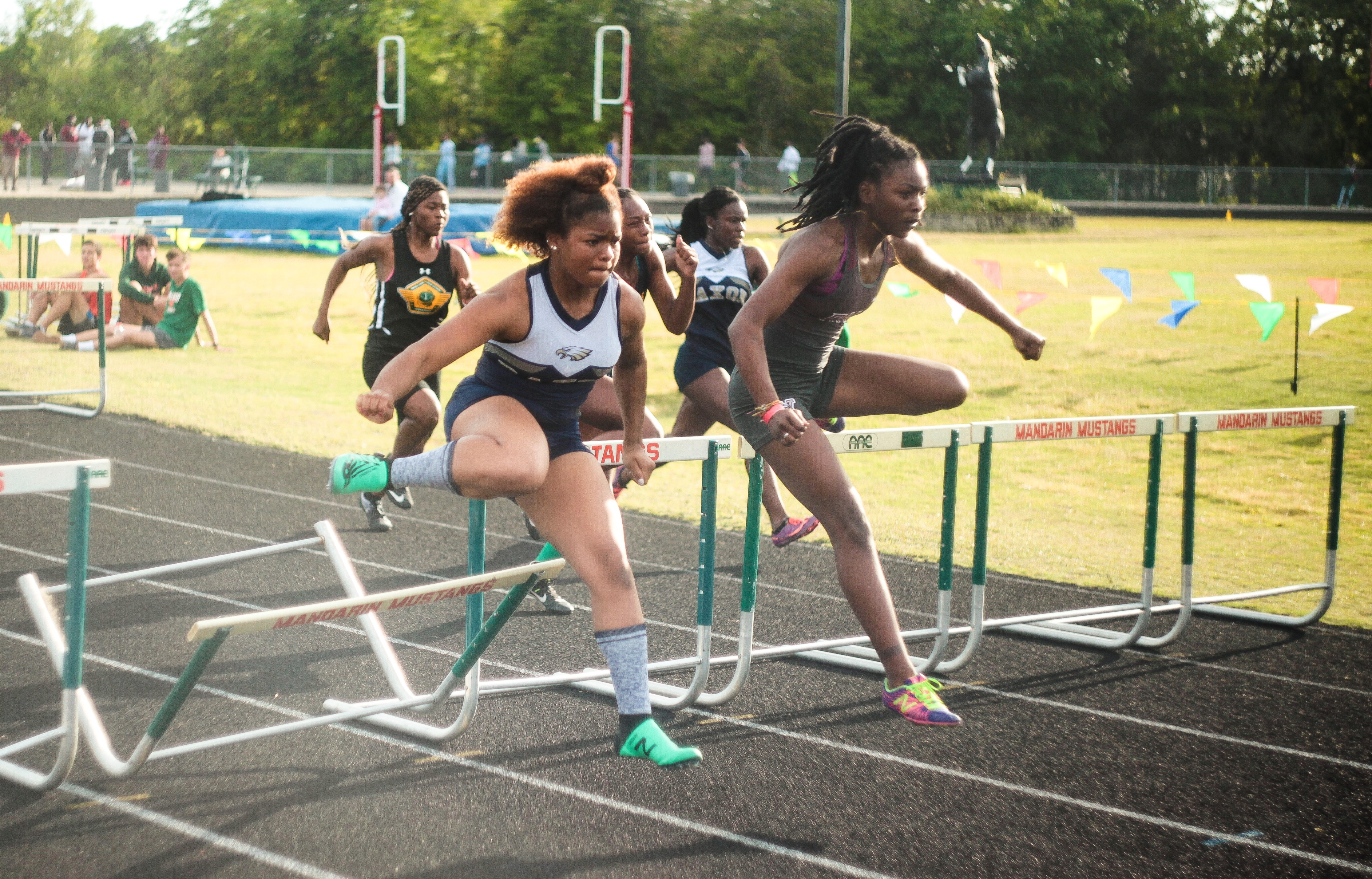 Duval County Public Schools student-athletes running on track jumping over hurdles