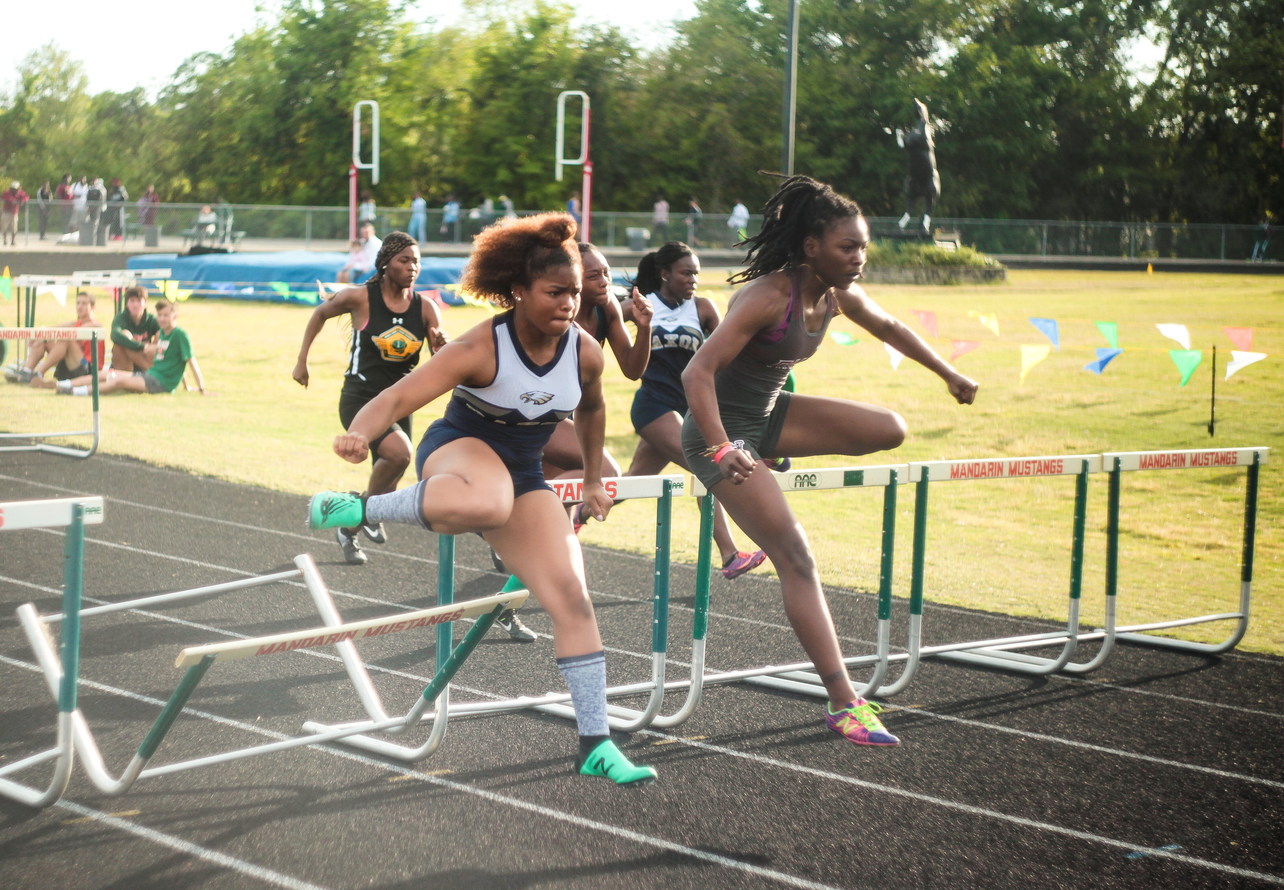 Duval County Public Schools High school track and field, two girls going over hurdles