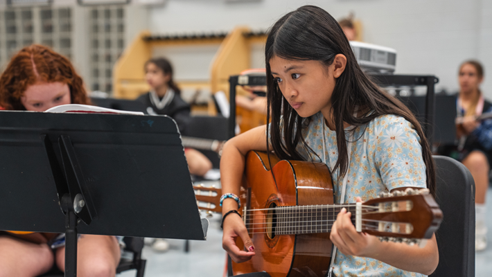 Duval County Public Schools middle school student playing the guitar and reading sheet music