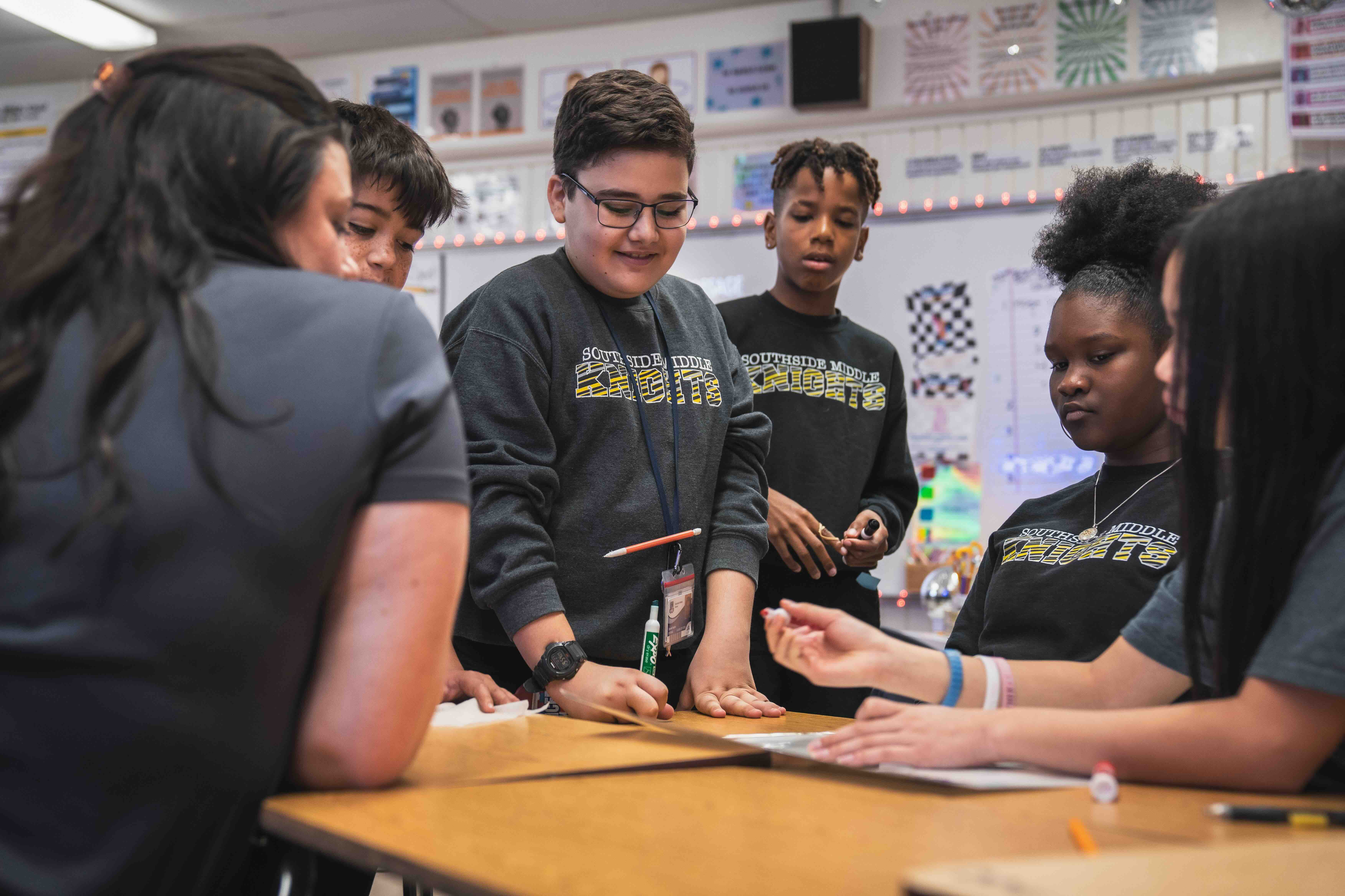 Group of 5 students and a teacher working together.