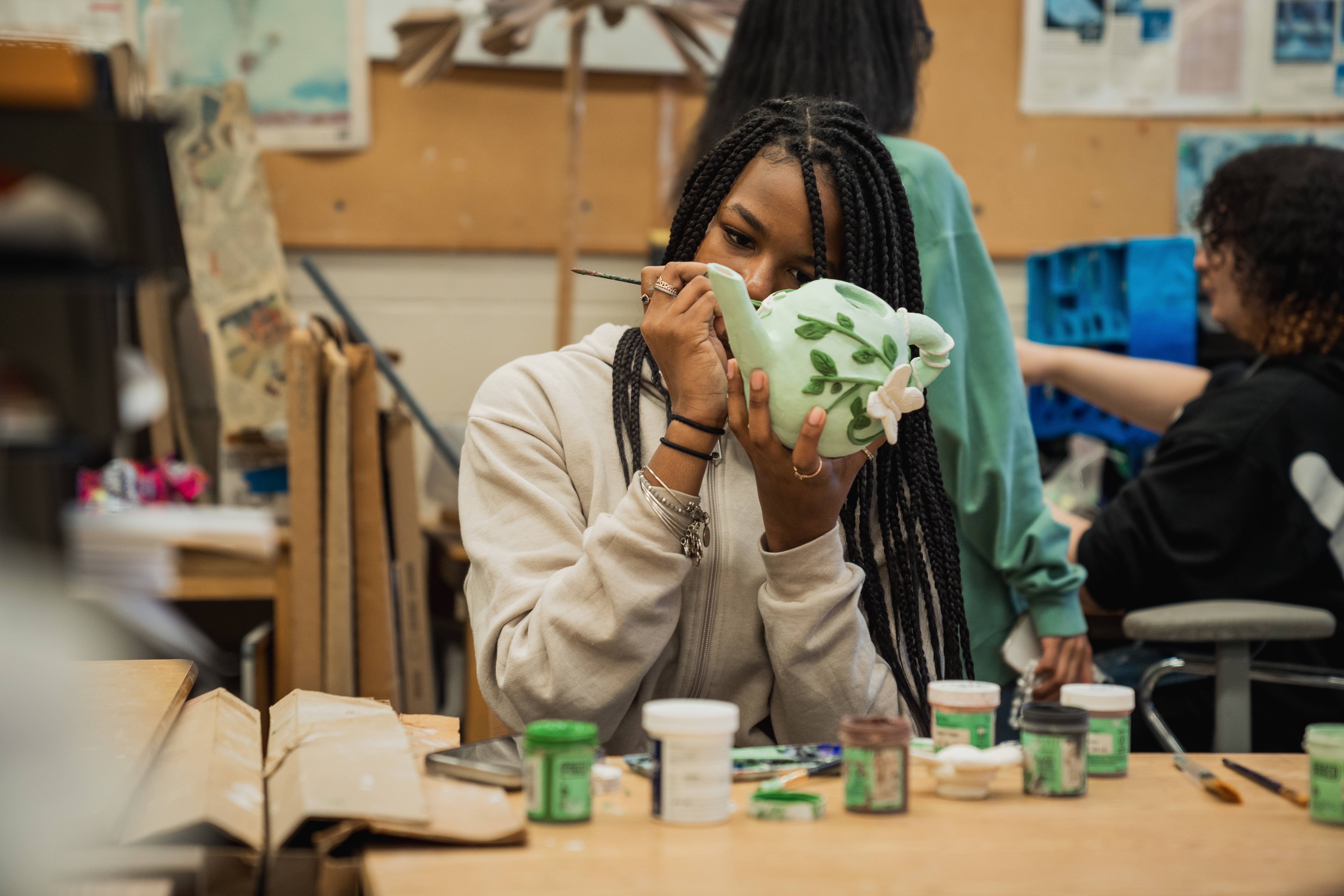 Paxon High School student paints a ceramic project in art class