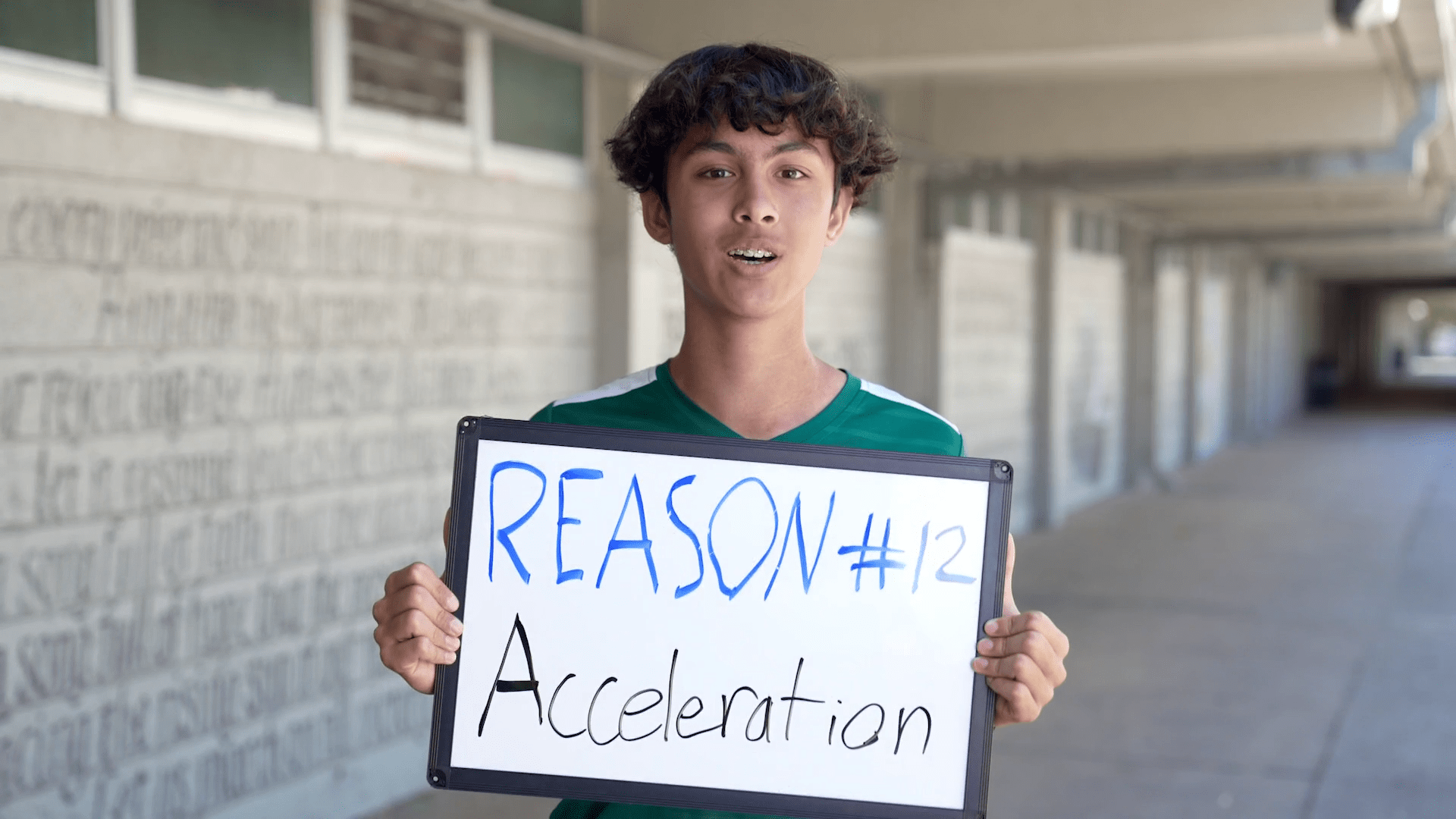 Boy holding a sign that states "Reason #12, Acceleration"