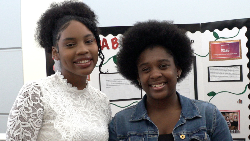 Two students in the African American Summer Writing institute smile in front of project