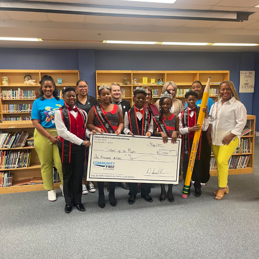 students, staff and partners smiling with large check and pencil