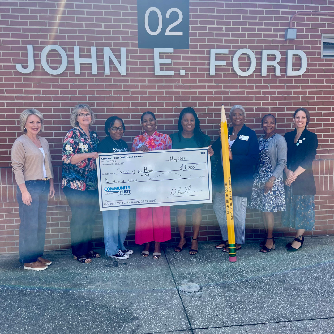 staff and partners smiling with large check and pencil