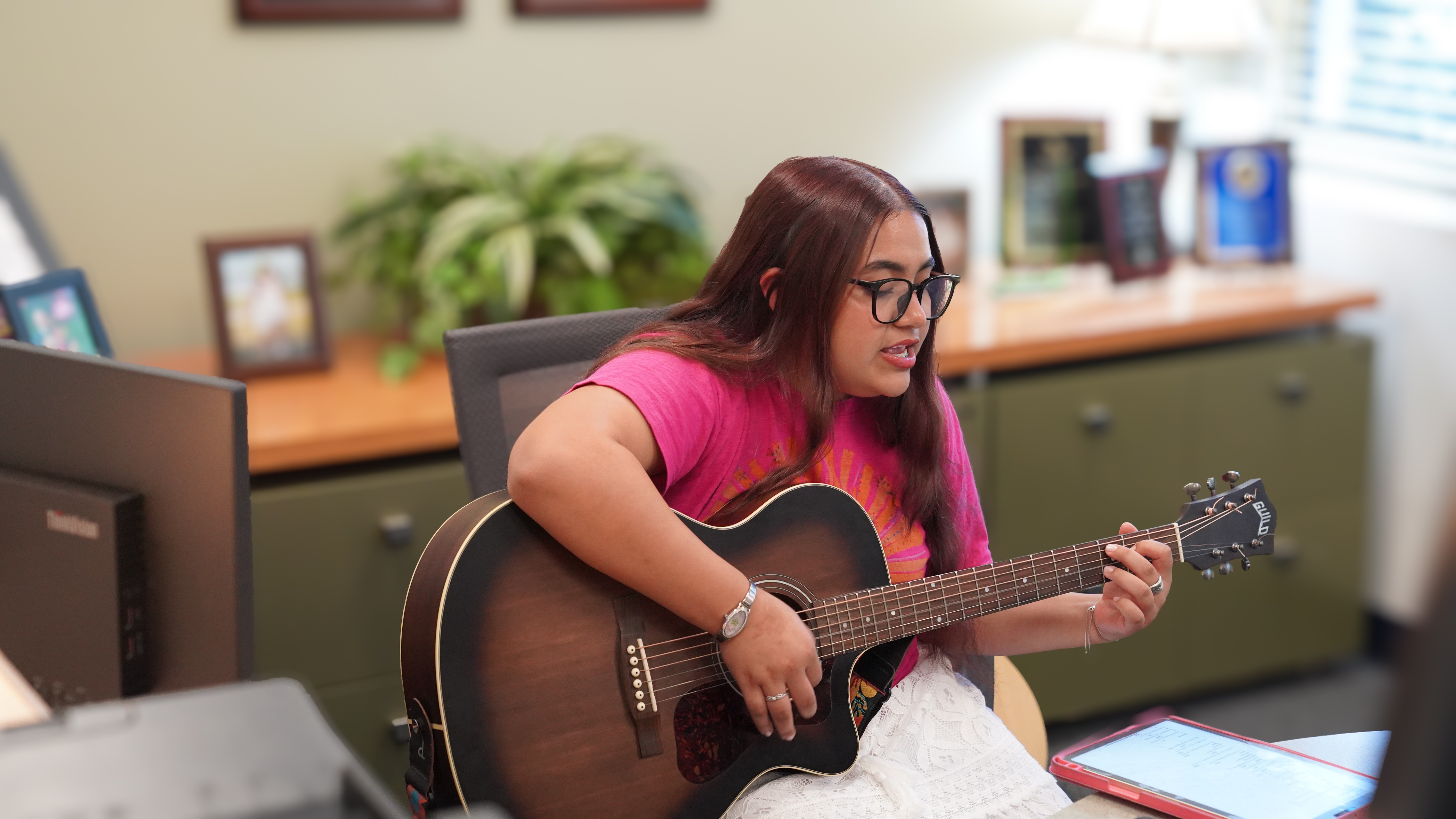 A Douglas Anderson School of the Arts student holds a guitar in the principal’s office, preparing to perform for the school’s new “Principal’s Desk” showcase.