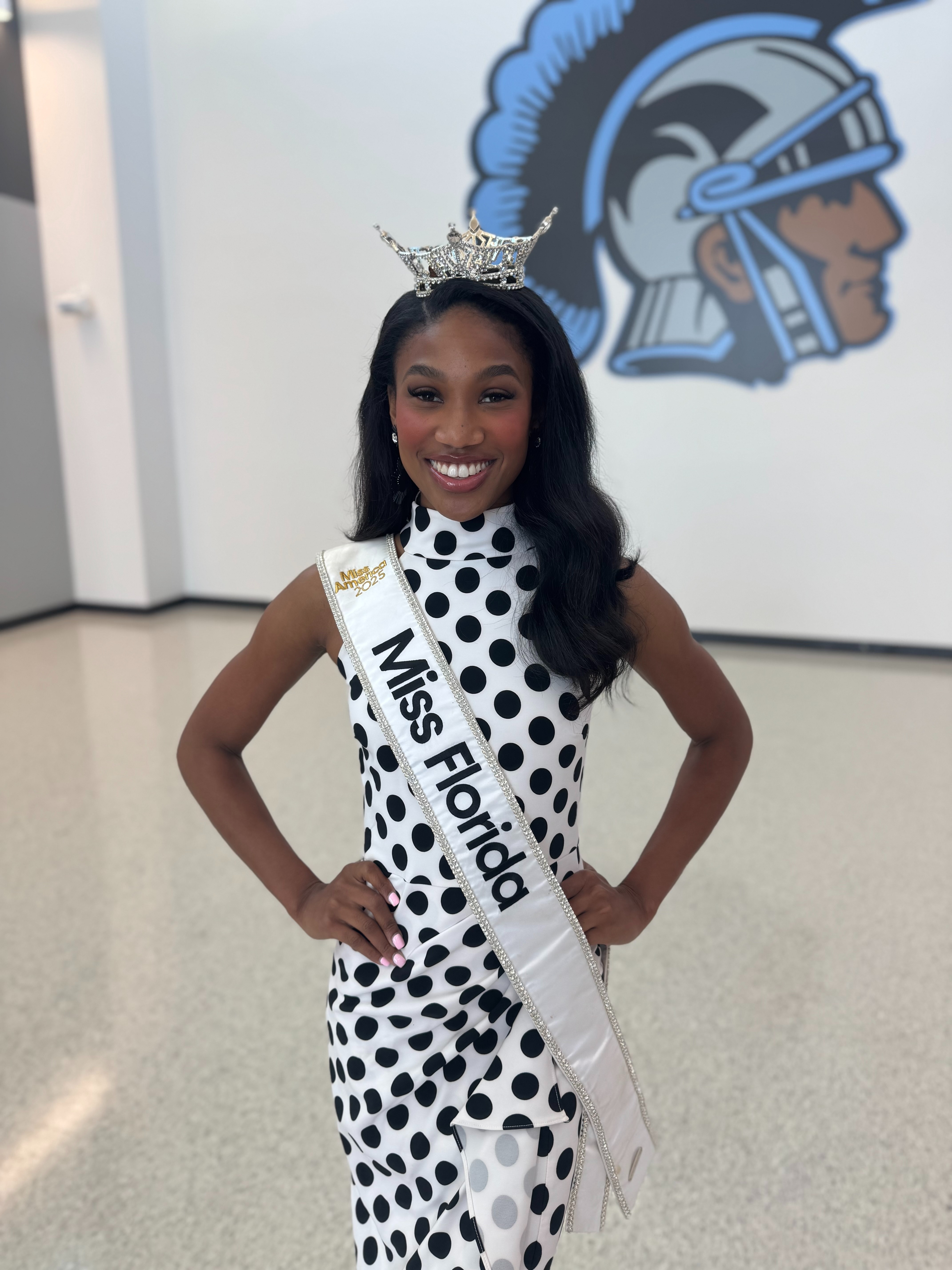 Photo shows Paris Richardson posing inside Ribault High School with the school's logo in the background