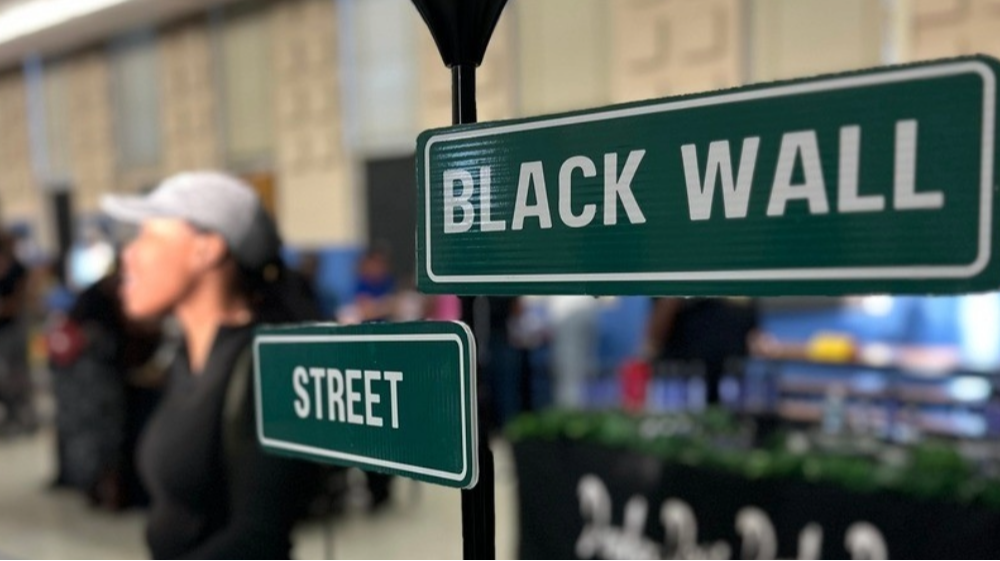 In the foreground is an image of make-shift street sign that reads: Black Wall Street