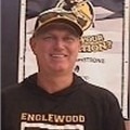 Man wearing a cap and a black shirt with "ENGLEWOOD" printed on it, smiling.