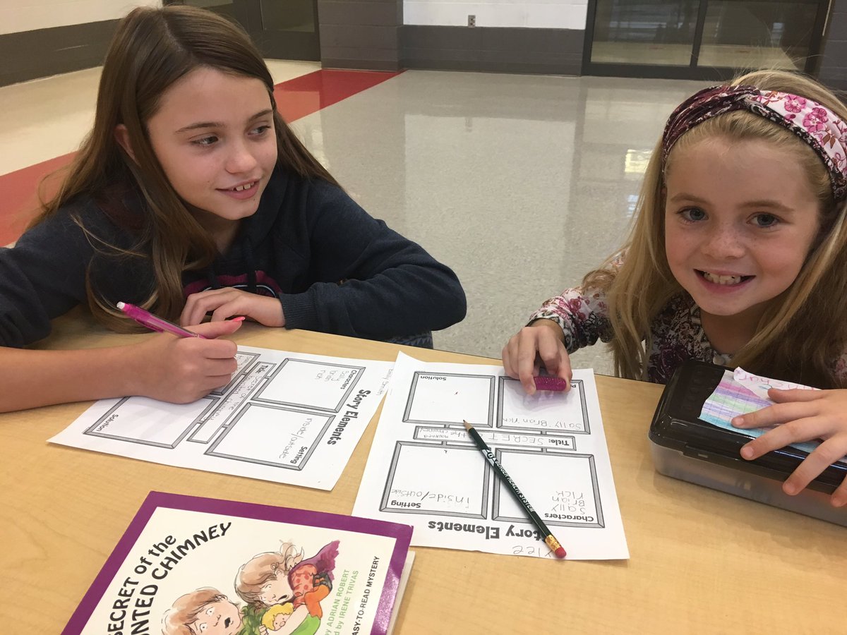 two elementary students at table with worksheets