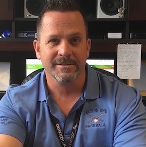 A man in a blue shirt sitting at a desk.