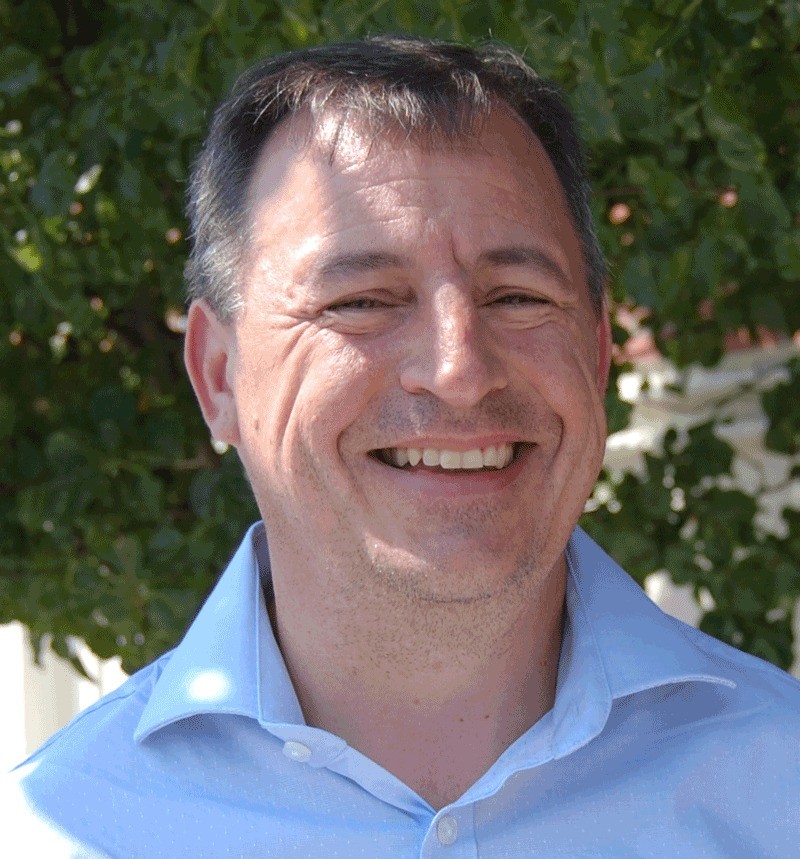 A man in a blue shirt smiling for a picture.