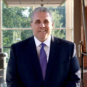 A man in a suit and tie smiling for the camera.