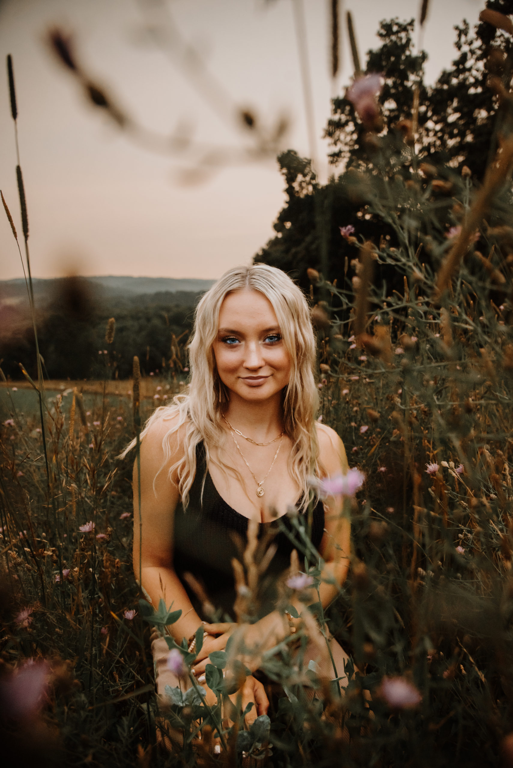 A blonde woman sitting in a field of wildflowers, enjoying the beauty of nature.