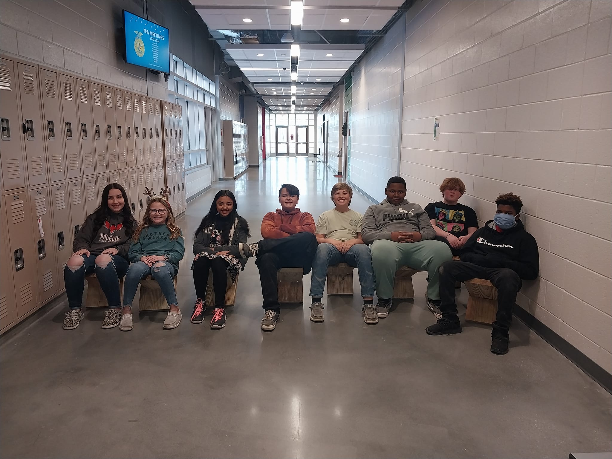 students sitting on handmade chairs in the hallway