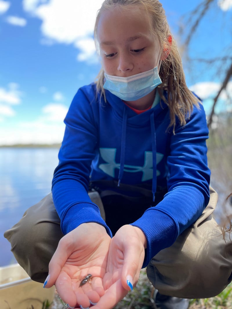 A young girl wearing a face mask and holding out her hands