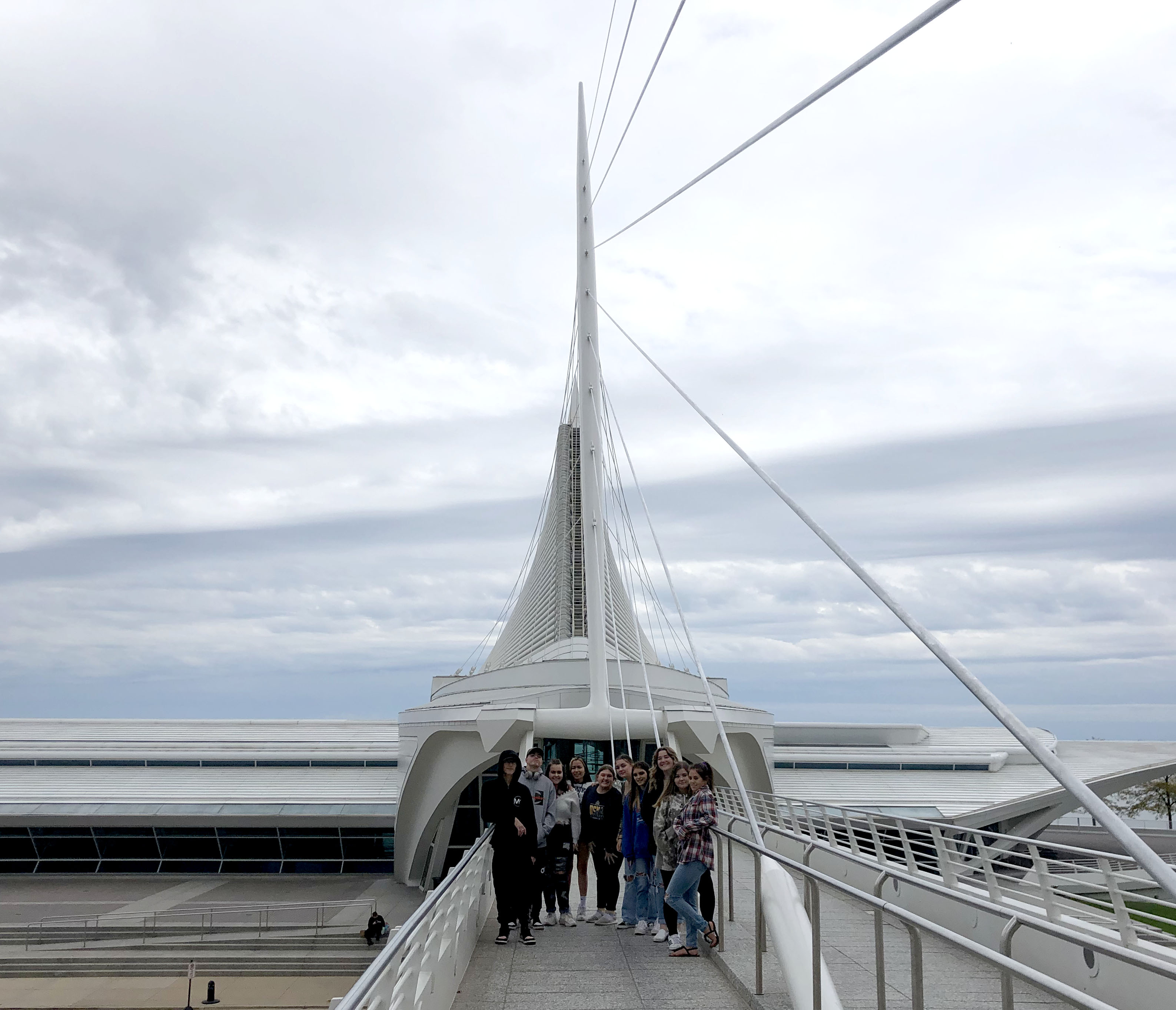 People walking on a bridge over a large building: A bustling bridge with pedestrians crossing over a towering urban structure.