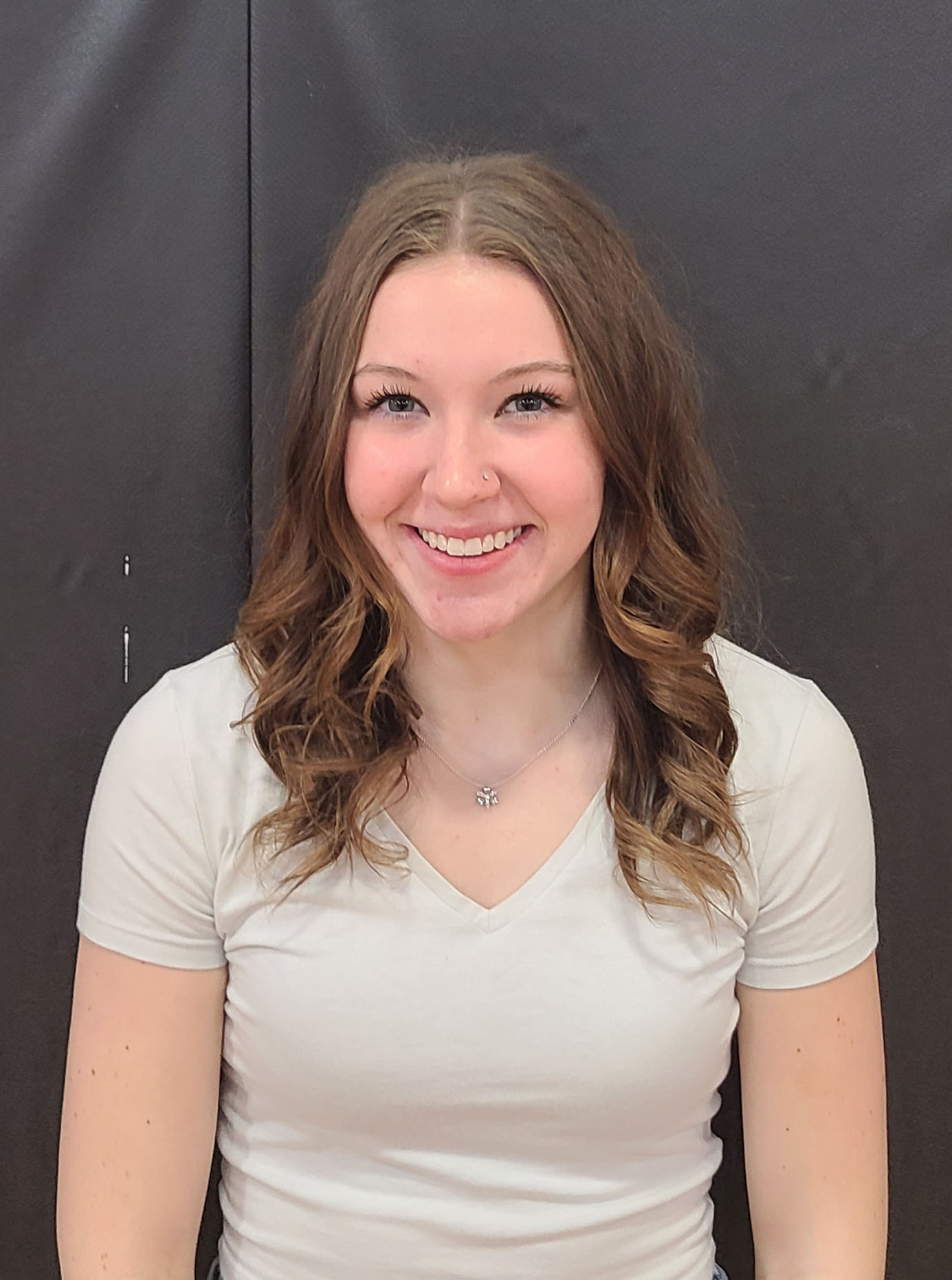 A girl in a white shirt sitting gracefully against a black background.