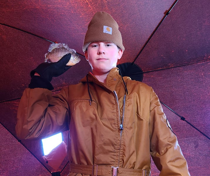 A man in a brown coat and hat, exuding a sense of style and sophistication.