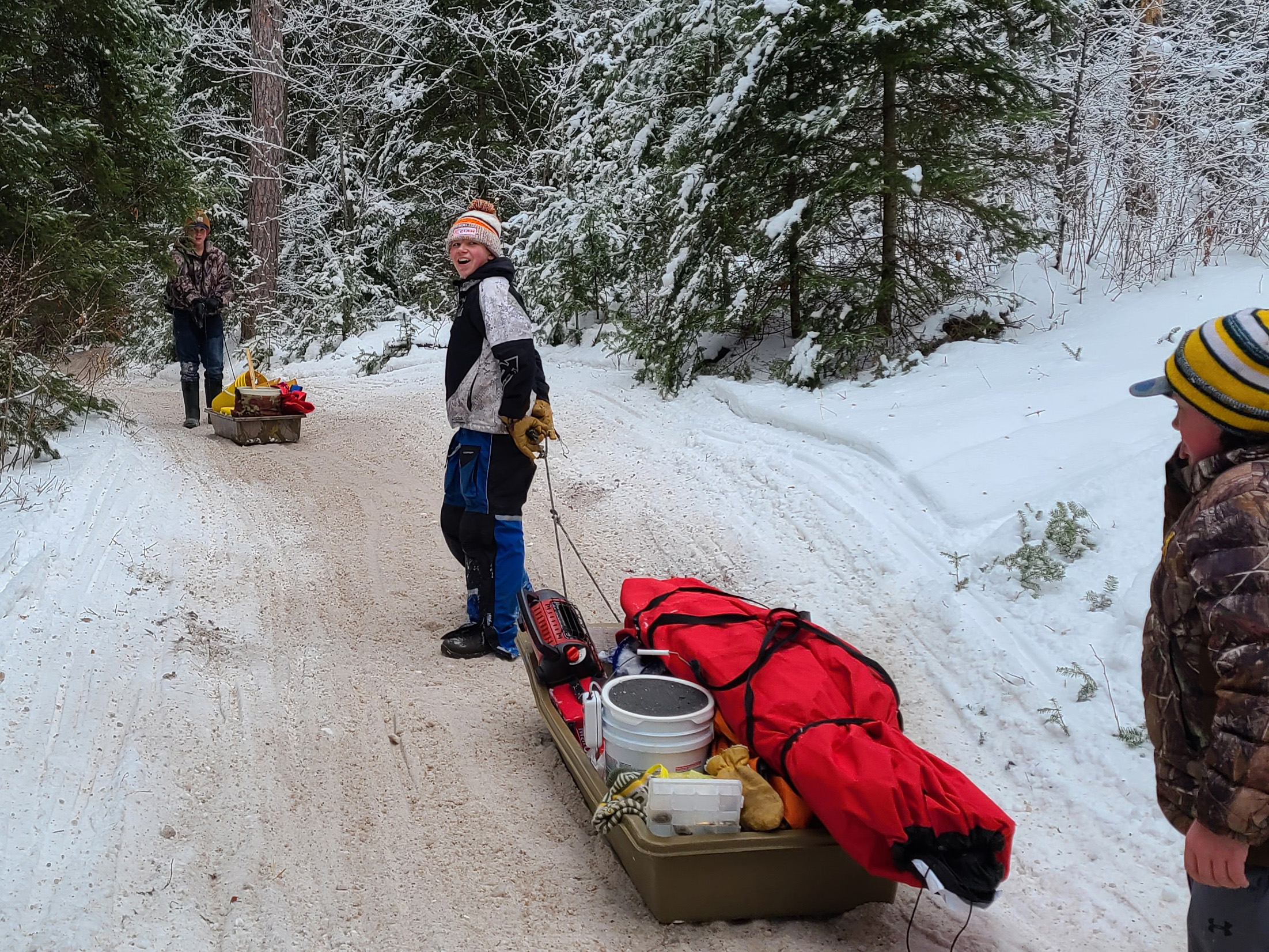 Man pulling sled on cart through snowy landscape.