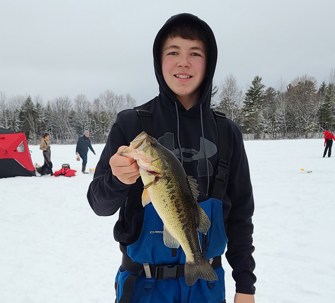 1. A young boy proudly holds up a large fish he caught in the snow-covered landscape.