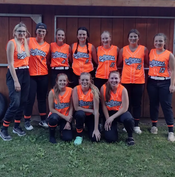 Softball team smiling together for group photo.