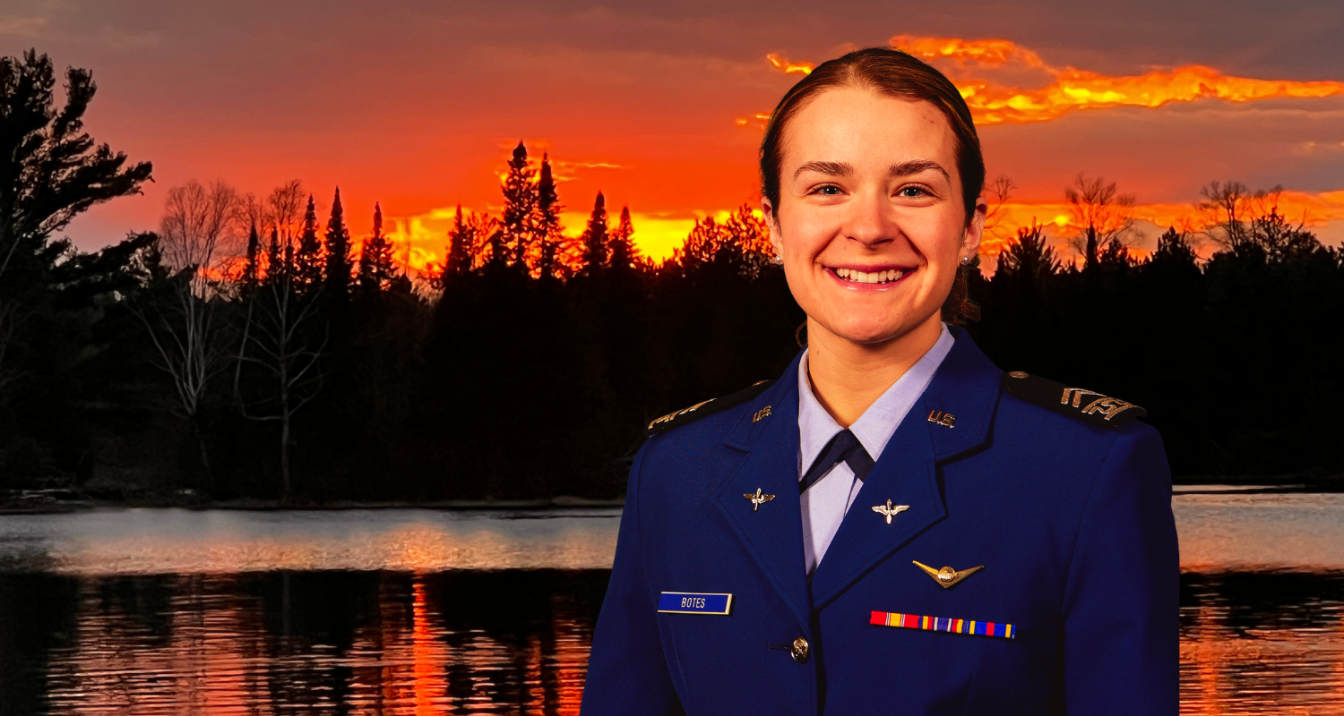 A woman in uniform standing by a serene lake, exuding confidence and professionalism.