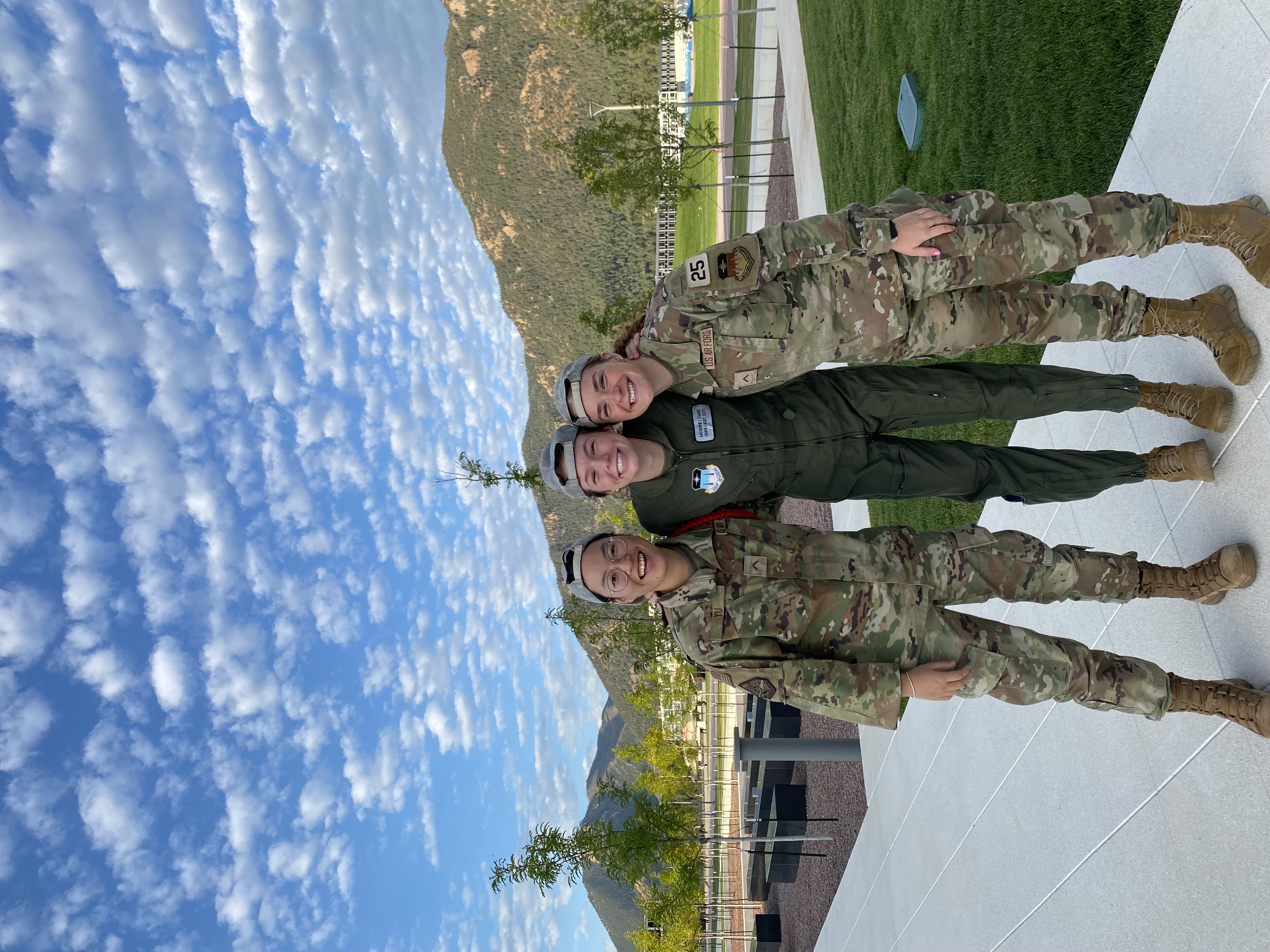 Three soldiers in uniform standing on a concrete floor.