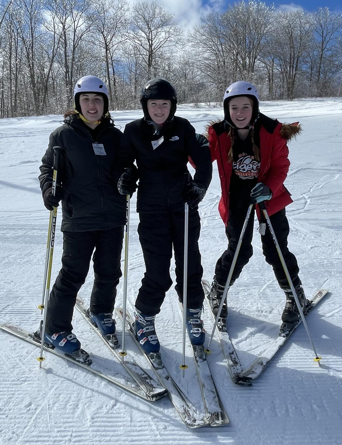 Three women skiing down a snowy slope.