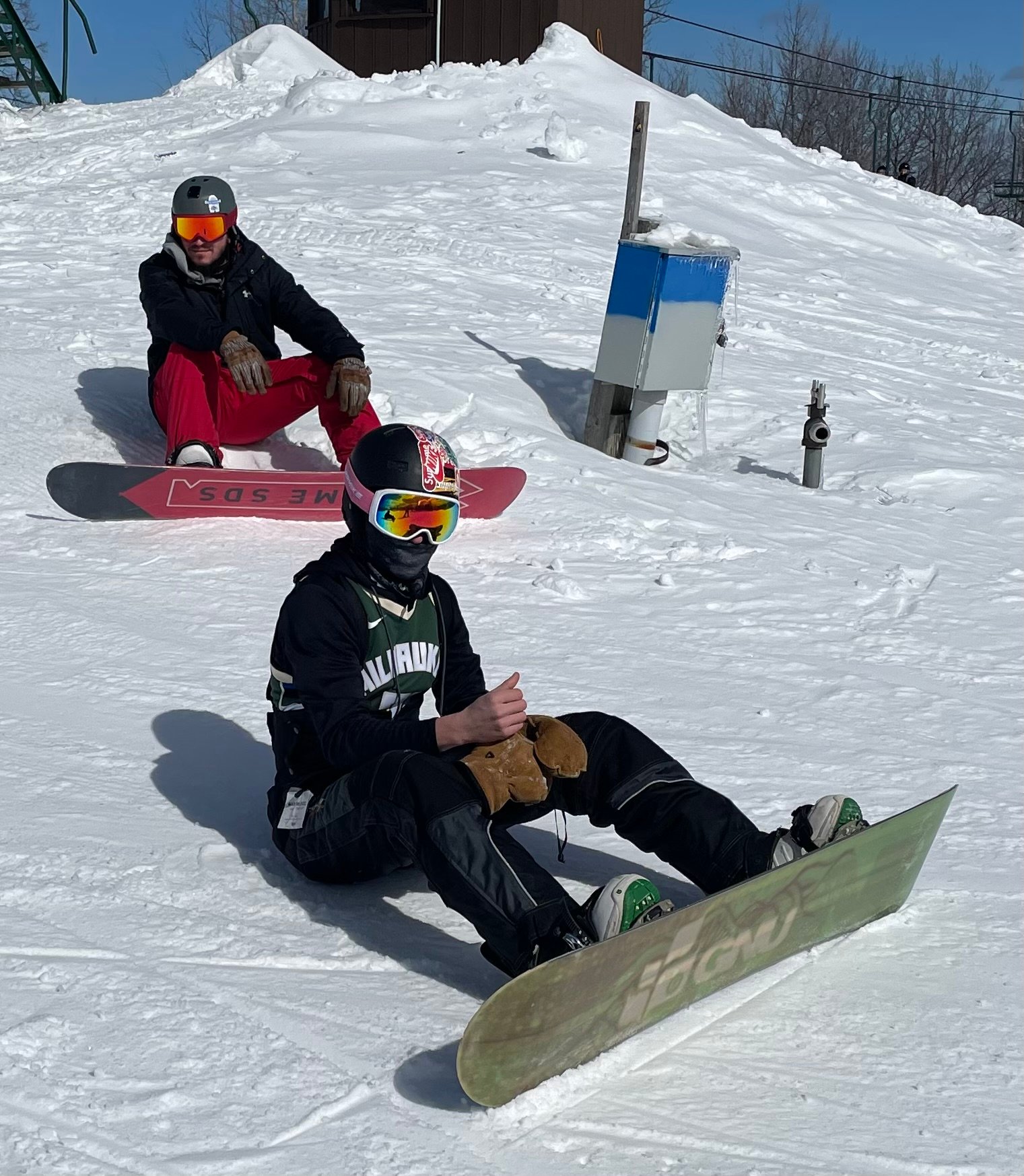 A young men sitting on snow with snowboards