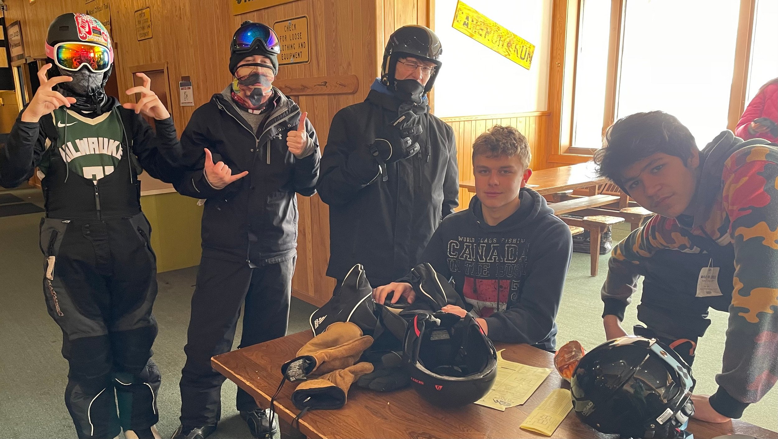 A cheerful group of young people in ski gear smiling for a photo, capturing their excitement on the slopes.