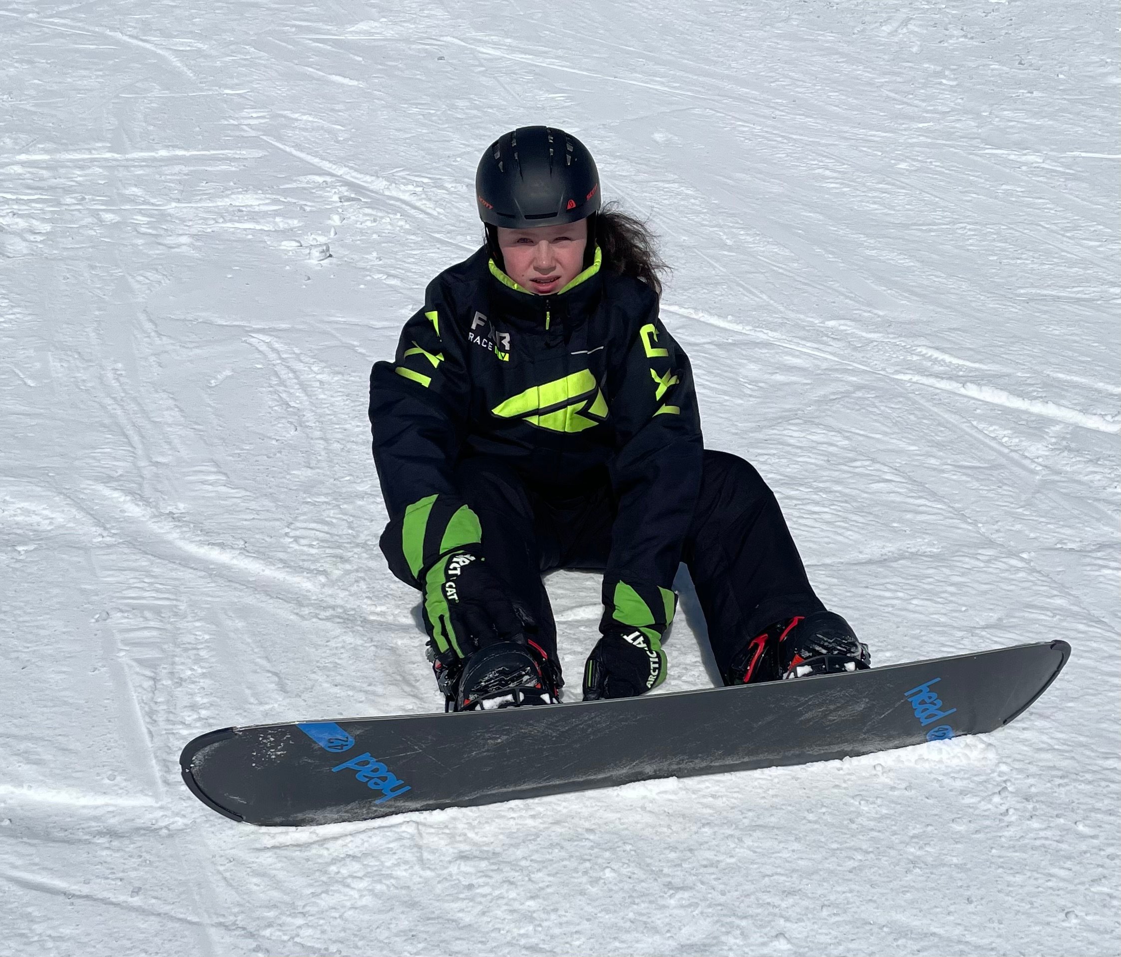 A young men sitting on snow with snowboards