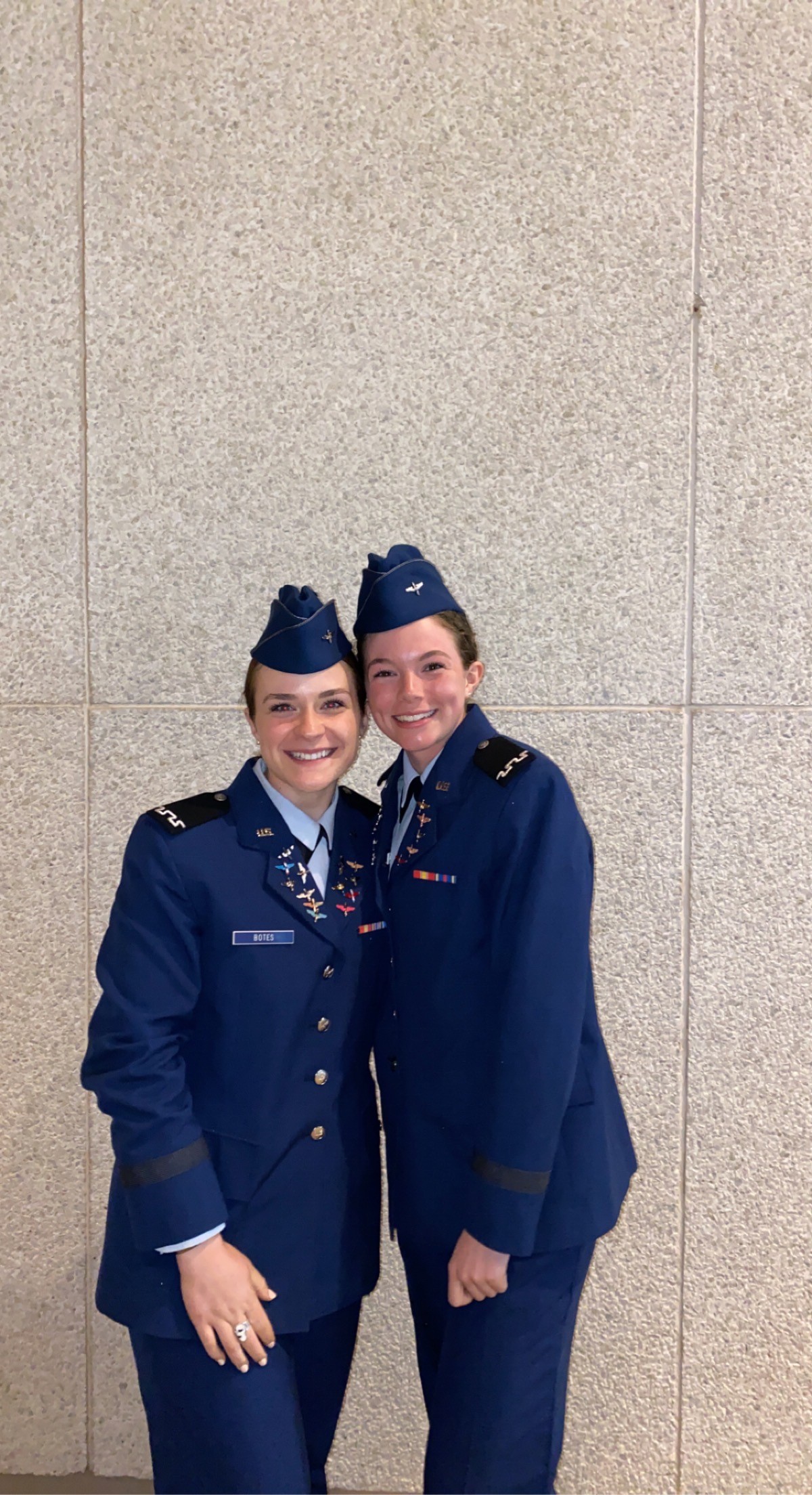 Two women in blue uniforms standing next to each other, possibly colleagues or friends.