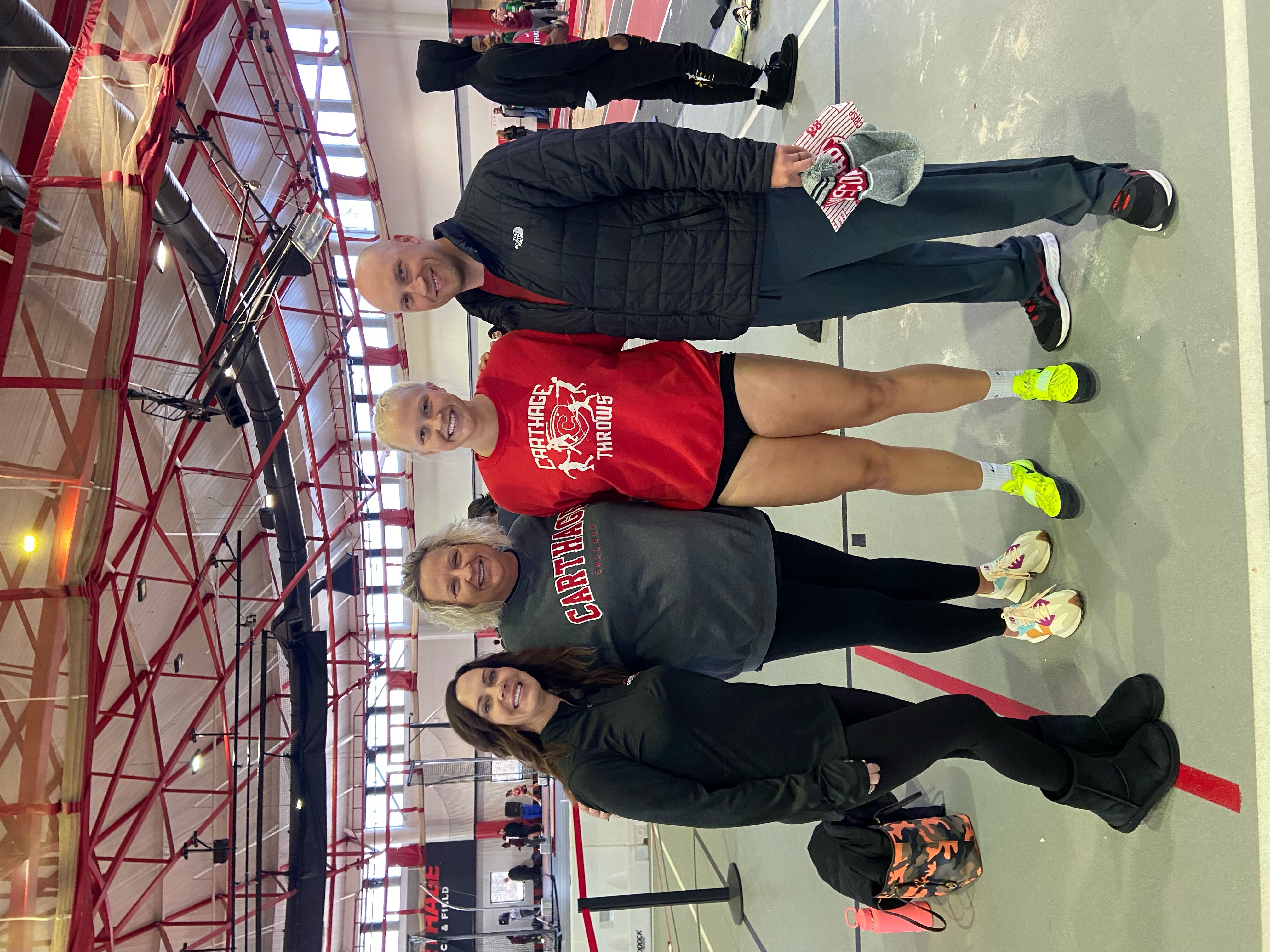 Four people standing on a tennis court.