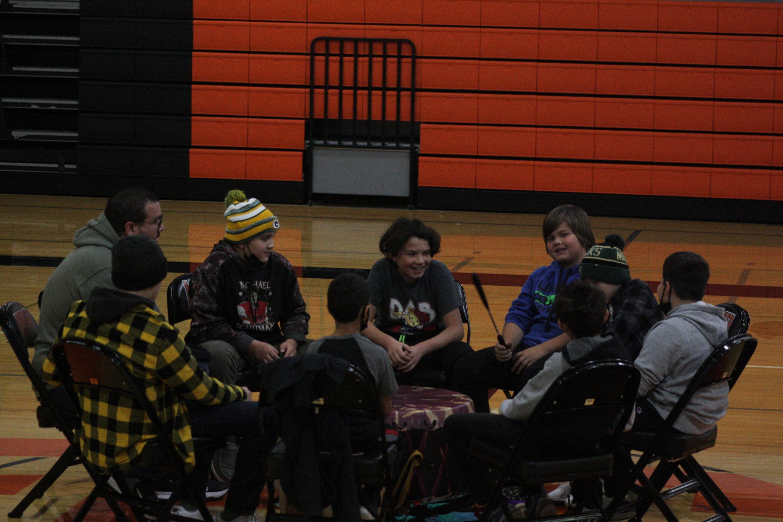 A group of people sitting around each other on a basketball court