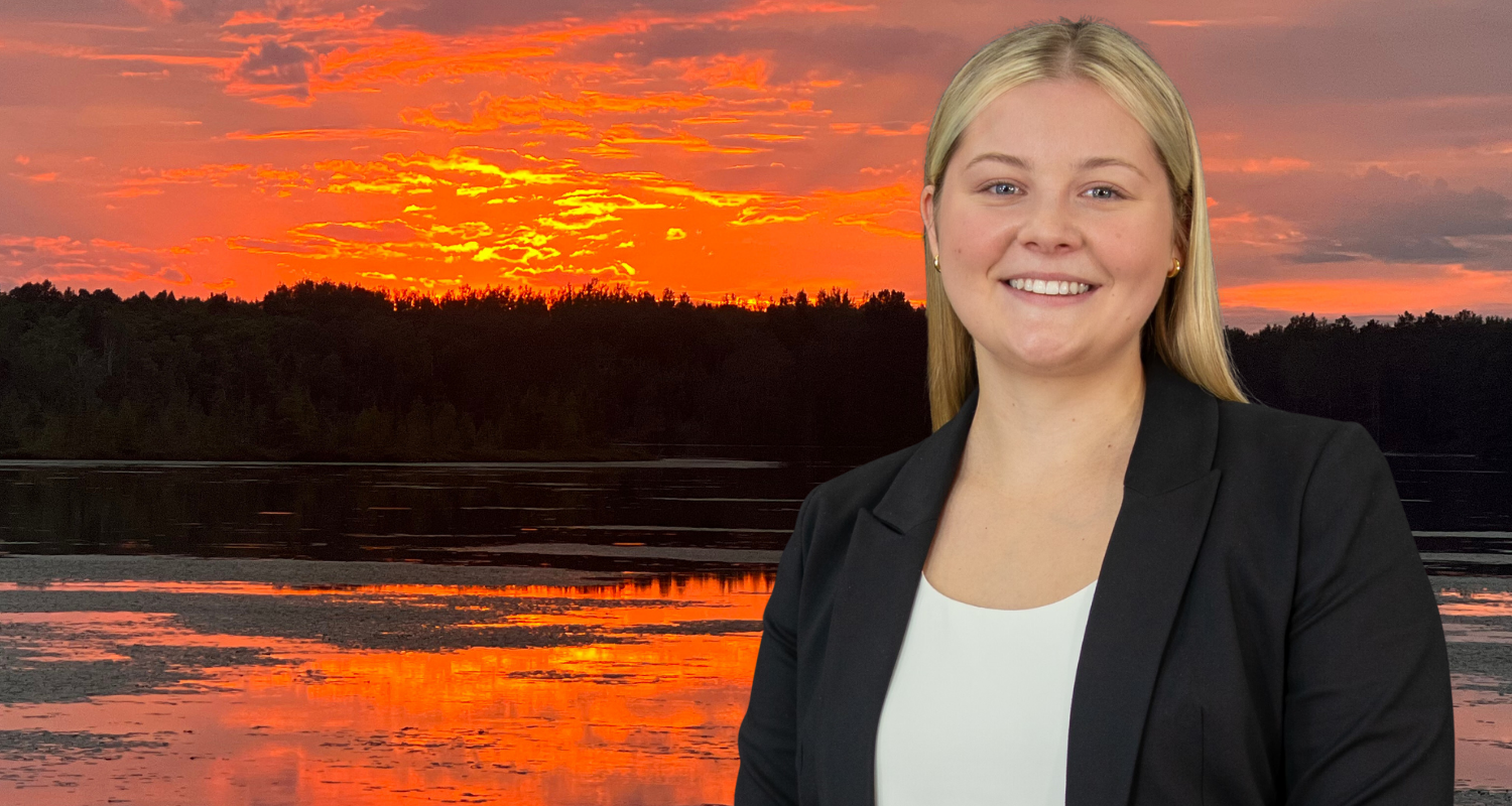 A professional woman in a business suit standing confidently by a serene lake, exuding poise and determination.